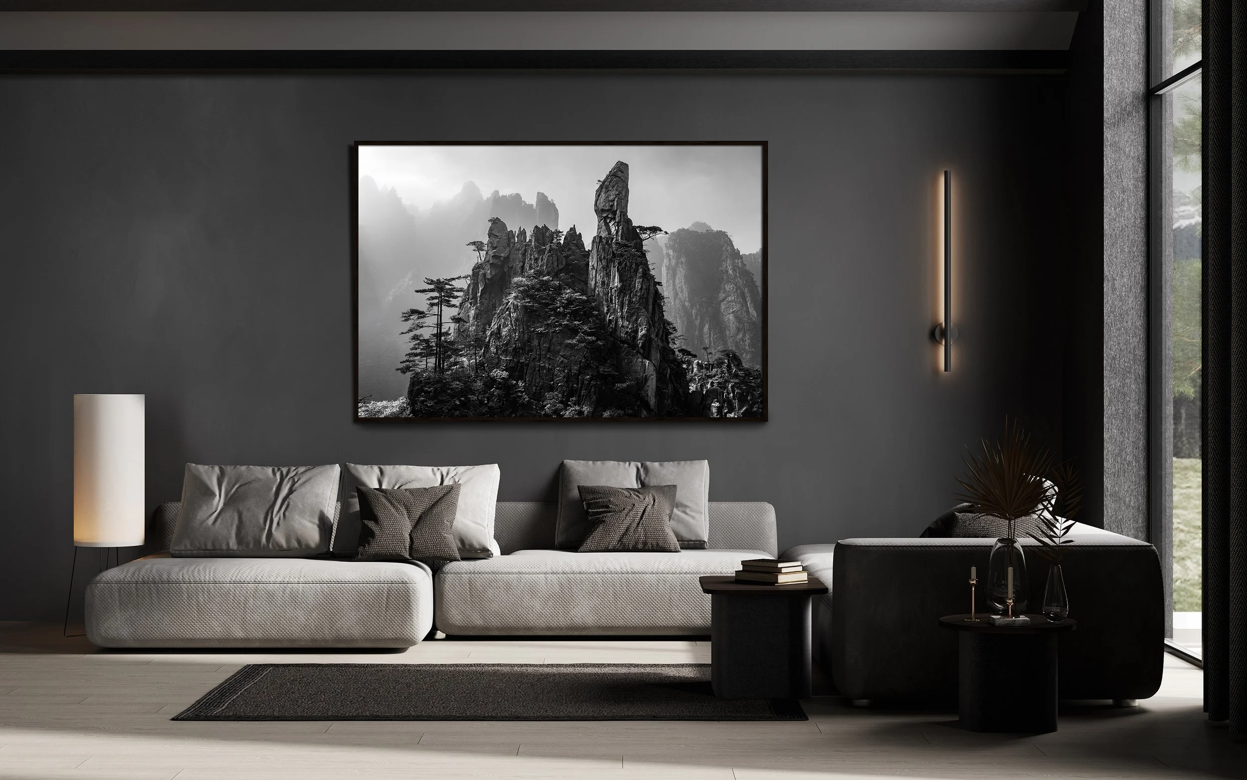 Modern living room with dark gray wall, white sofa, black pillows, black coffee table, and a large black-and-white mountain landscape photograph.