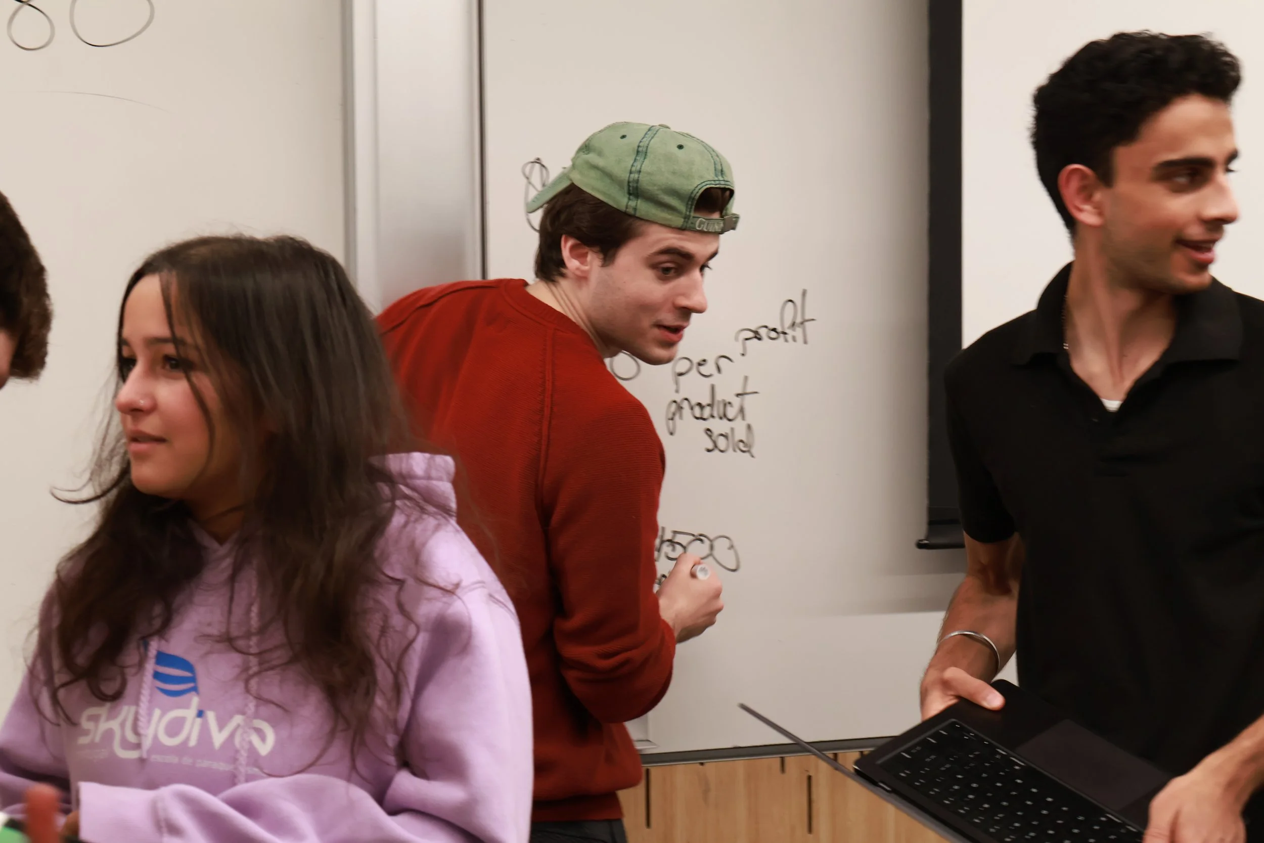 Northeastern University students brainstorming and mapping out business strategy on a whiteboard during a SimBus in-class simulation.