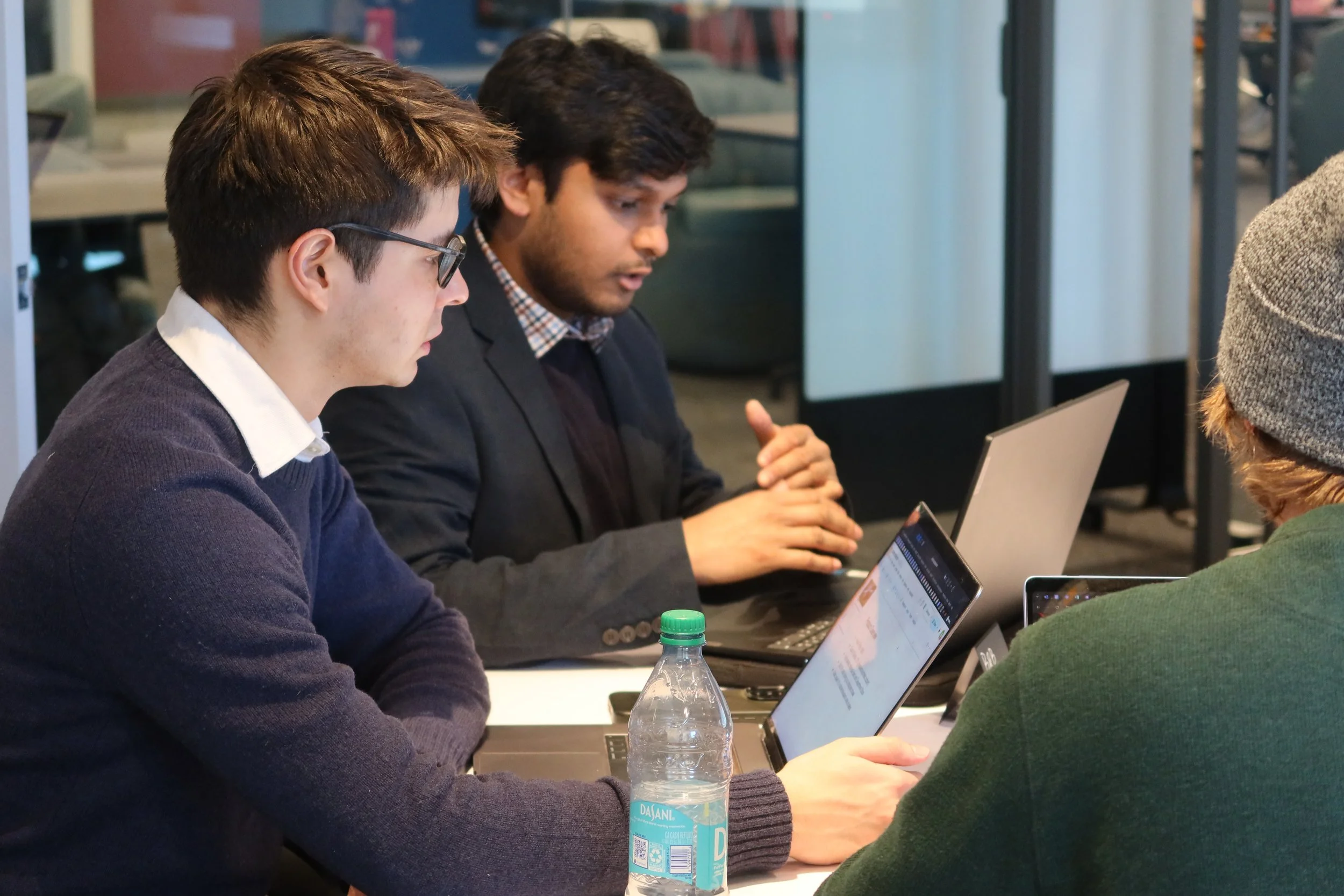Northeastern University students analyzing business strategy on laptops during the SimBus Game of Ventures experiential learning simulation.