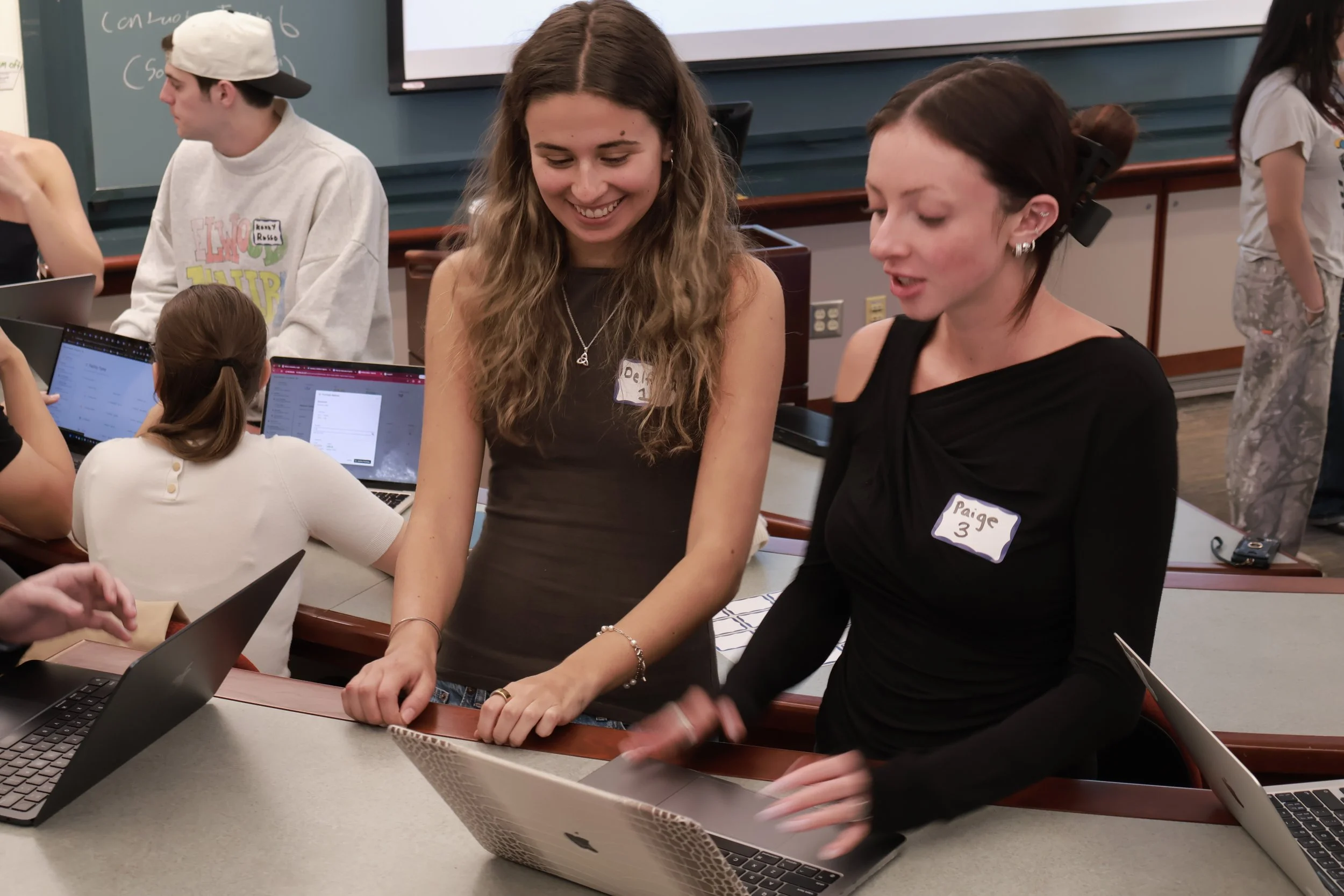 Student entrepreneurs analyzing data and discussing strategy over a laptop in a SimBus Simulation at Boston University.