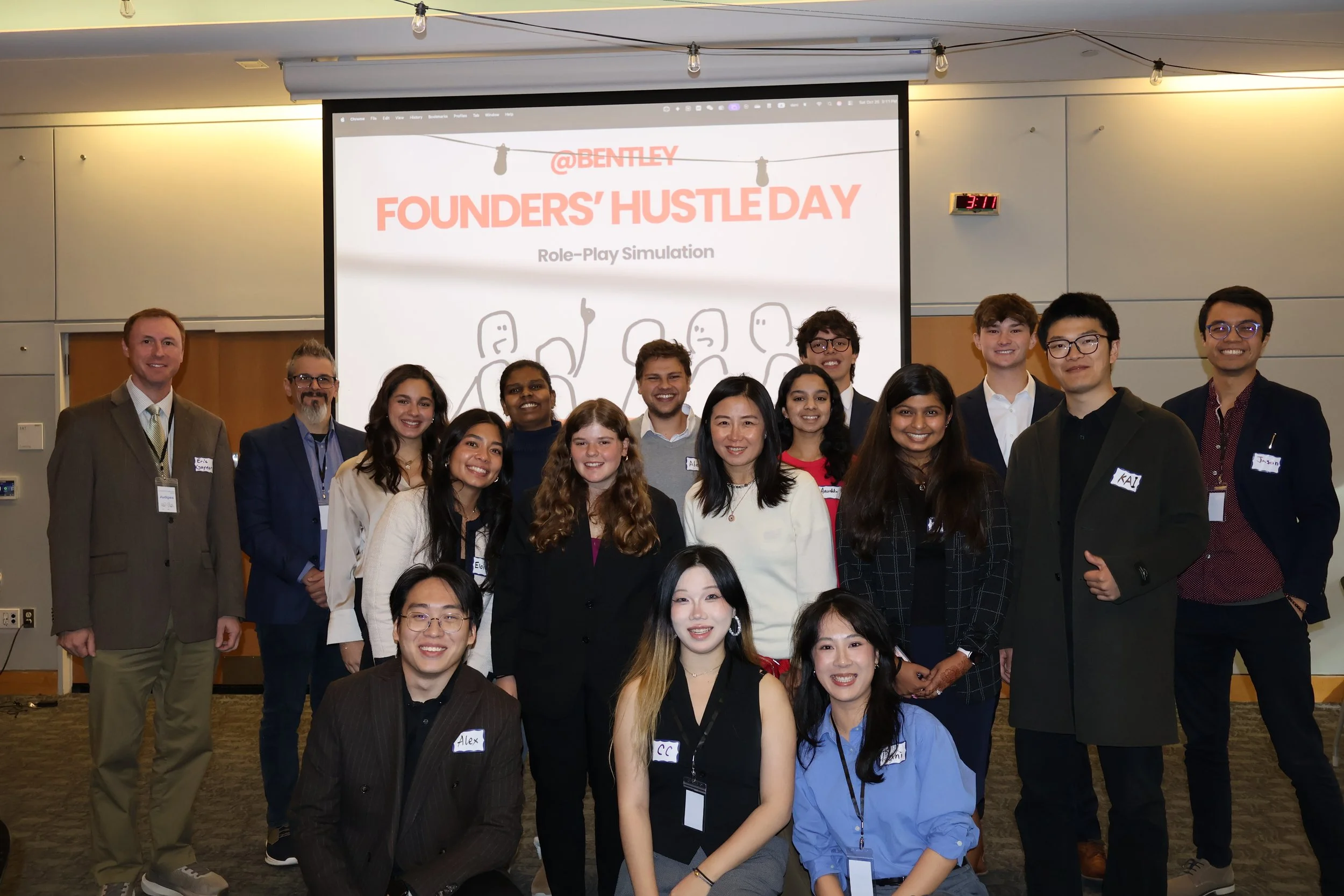 Bentley University students and professors posing together at the SimBus Founders' Hustle Day experiential learning role-play simulation.