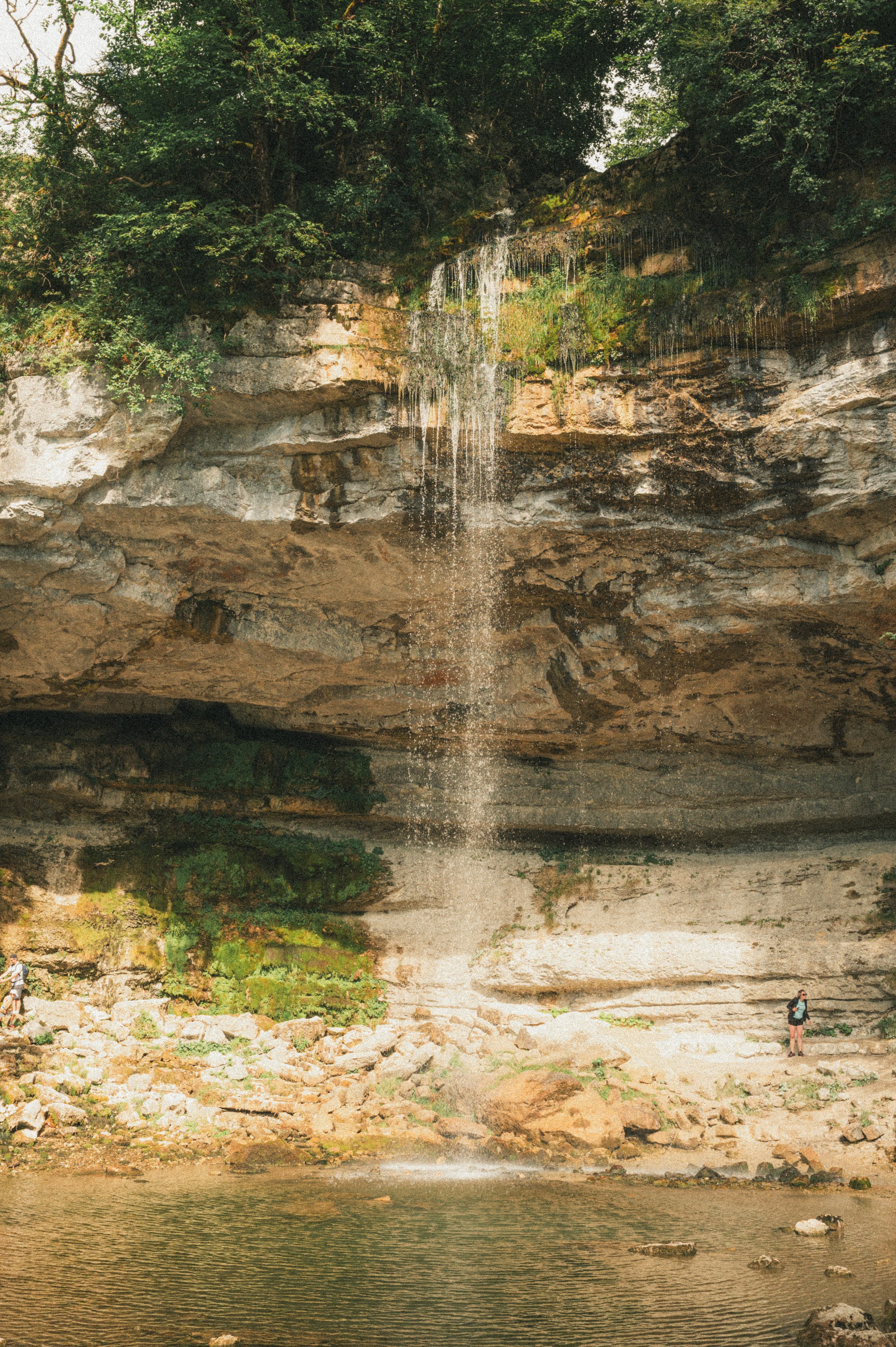 Chute d'eau à l'intérieur d'une grotte ou d'une formation rocheuse, avec des personnes à ses alentours.