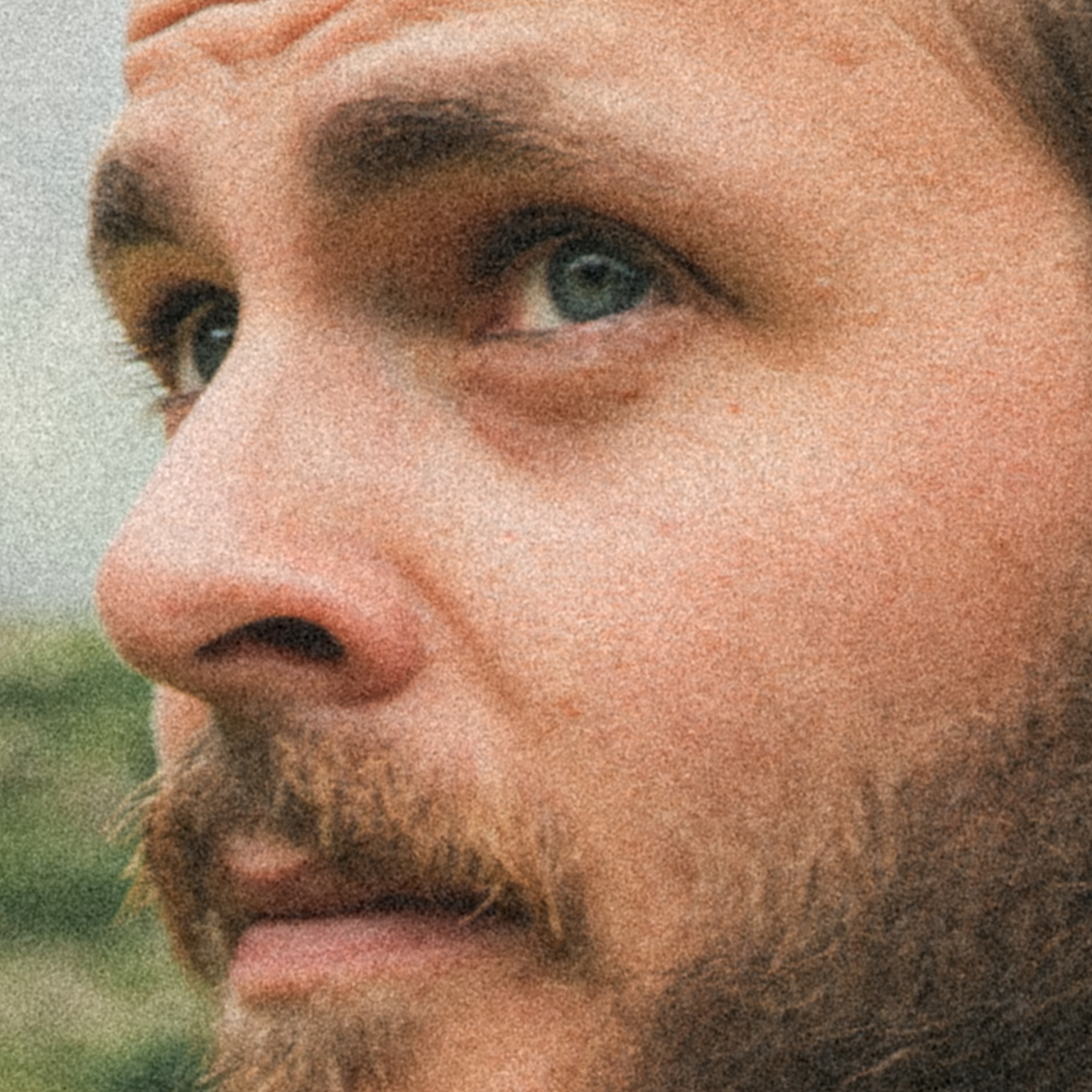 Un gros plan du visage d'une personne, montrant principalement l'œil, le nez et une partie de la barbe, avec un fond flou.