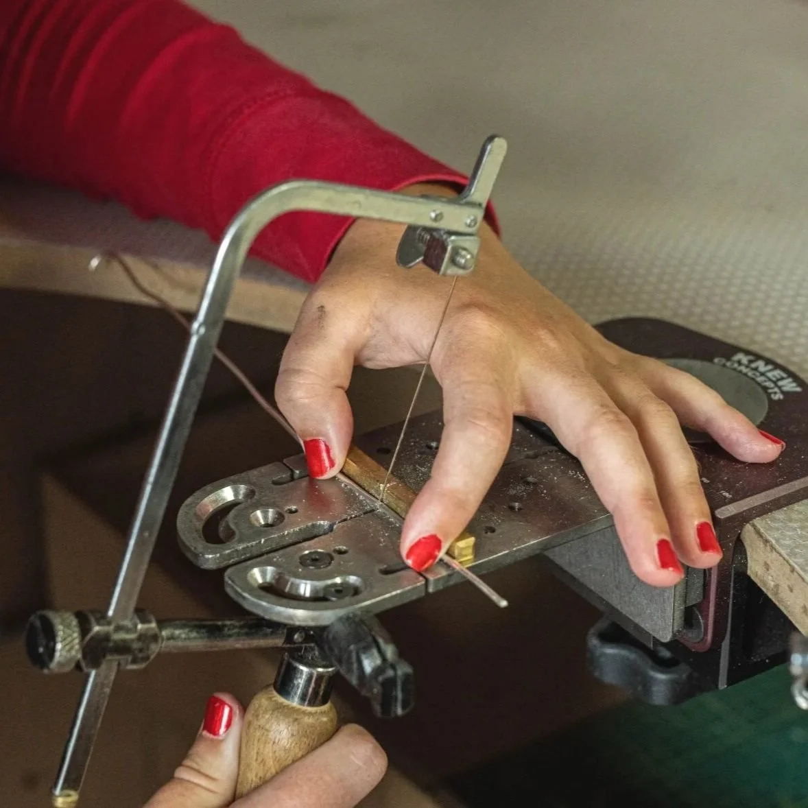 Using a jeweller's saw on a metal workbench to make a ring in a Bello creation workshop