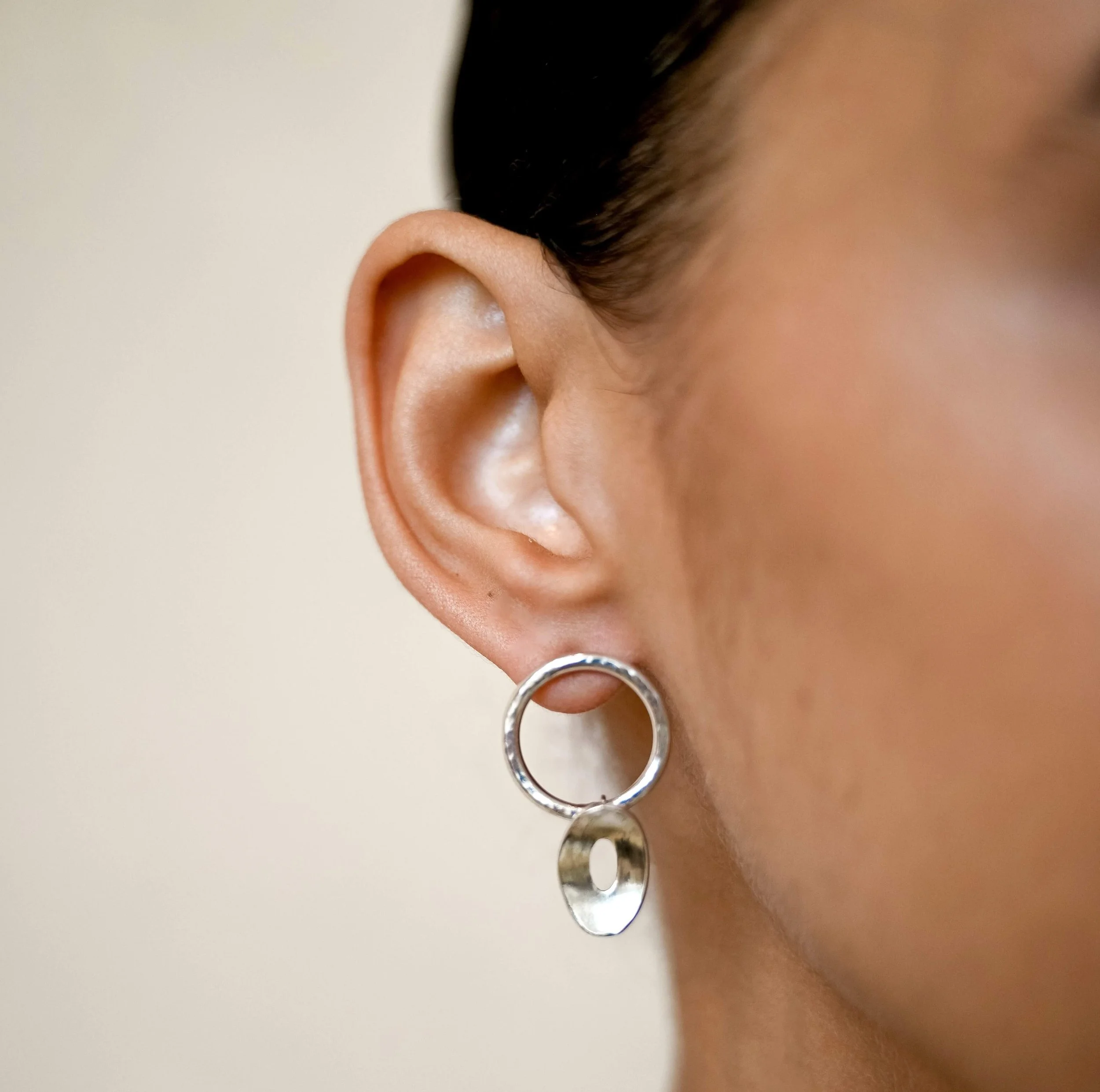 A model wearing a Sterling silver drop earrings with hammered circular tops and curved open oval drops from the Floating Ovals collection.