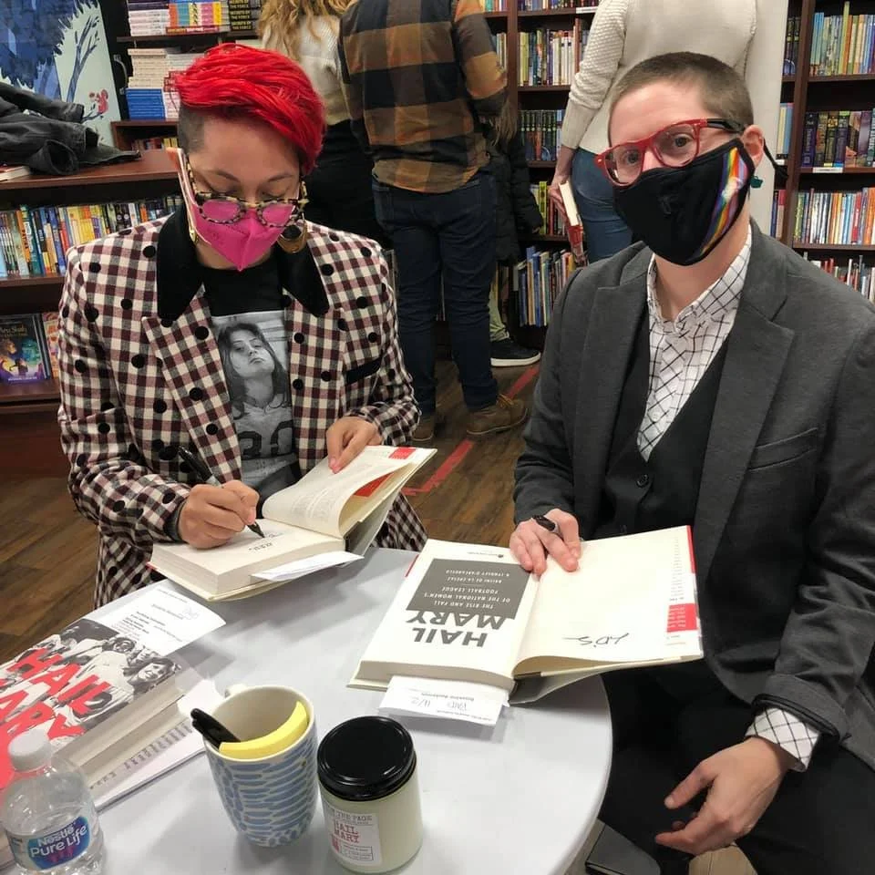Lyndsey D'Arcangelo and co-author Frankie de la Cretaz are signing copies of their book, Hail Mary: The Rise and Fall of the Women's National Football League. They are both wearing masks to cover their nose and mouth because of COVID-19.