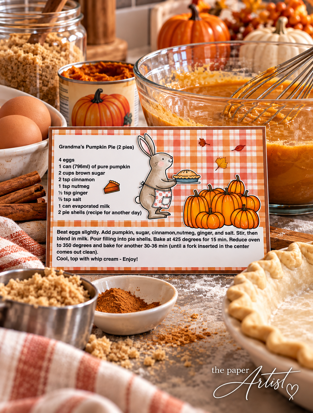 Handmade pumpkin pie recipe card displayed on a kitchen counter surrounded by baking ingredients and a mixing bowl.