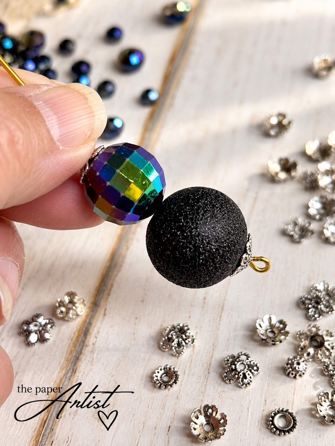 Two decorative beads connected with an eye pin to form a handmade spider body
