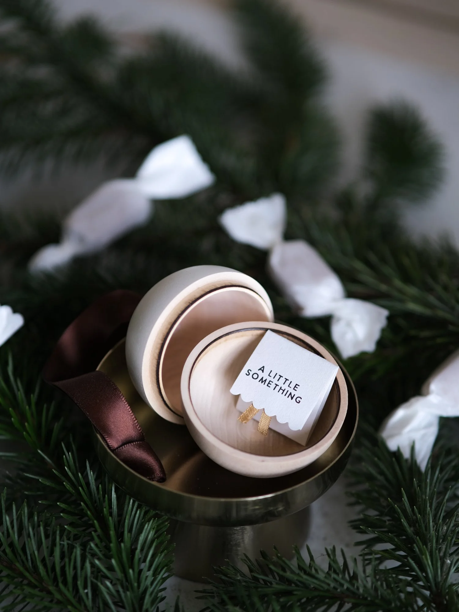 Wooden and white Christmas gift bauble with a removable lid, hanging from a Christmas tree with a space inside for a handwritten message, gift or surprise.