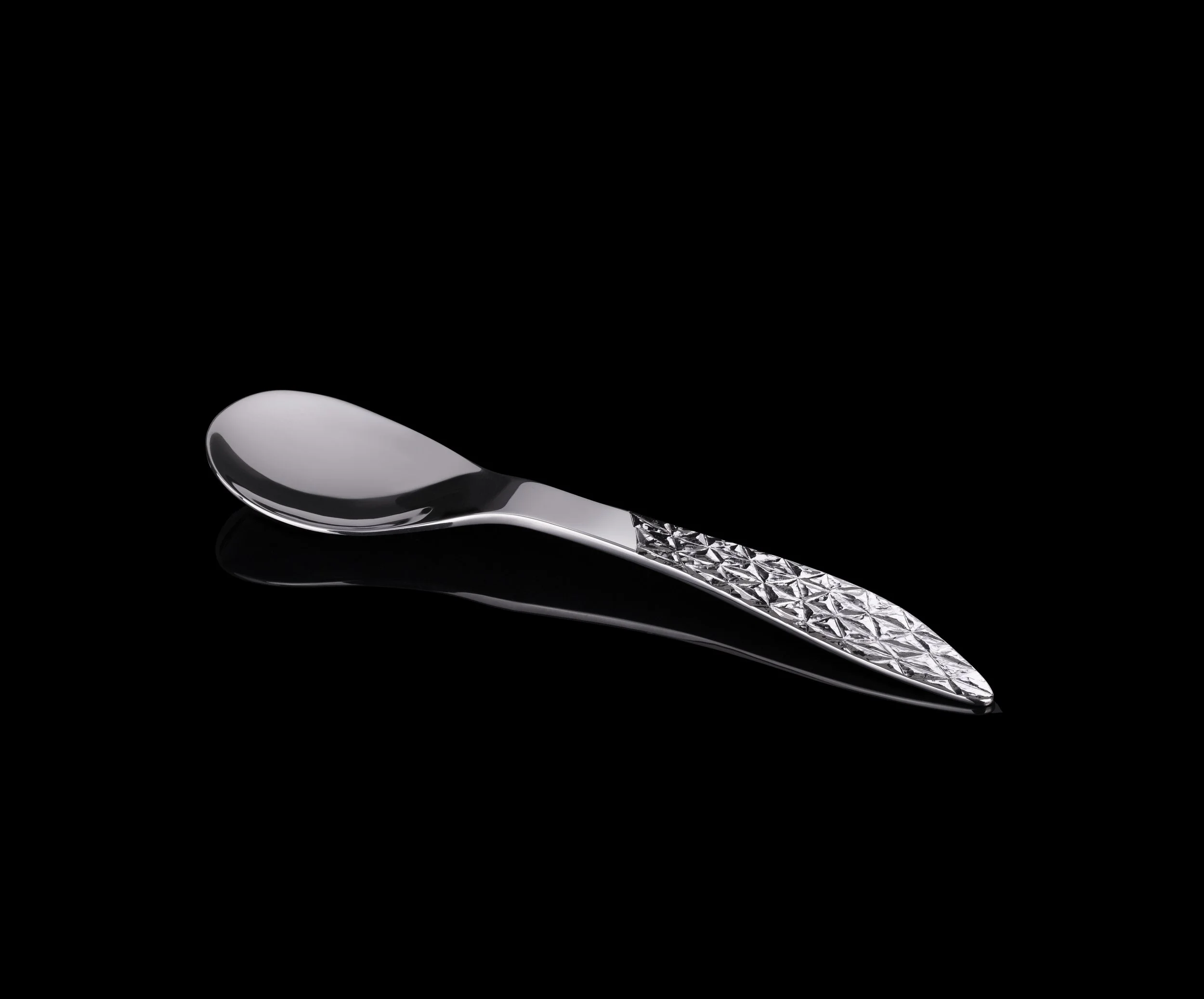 Silver luxury spoon with textured handle on black background
