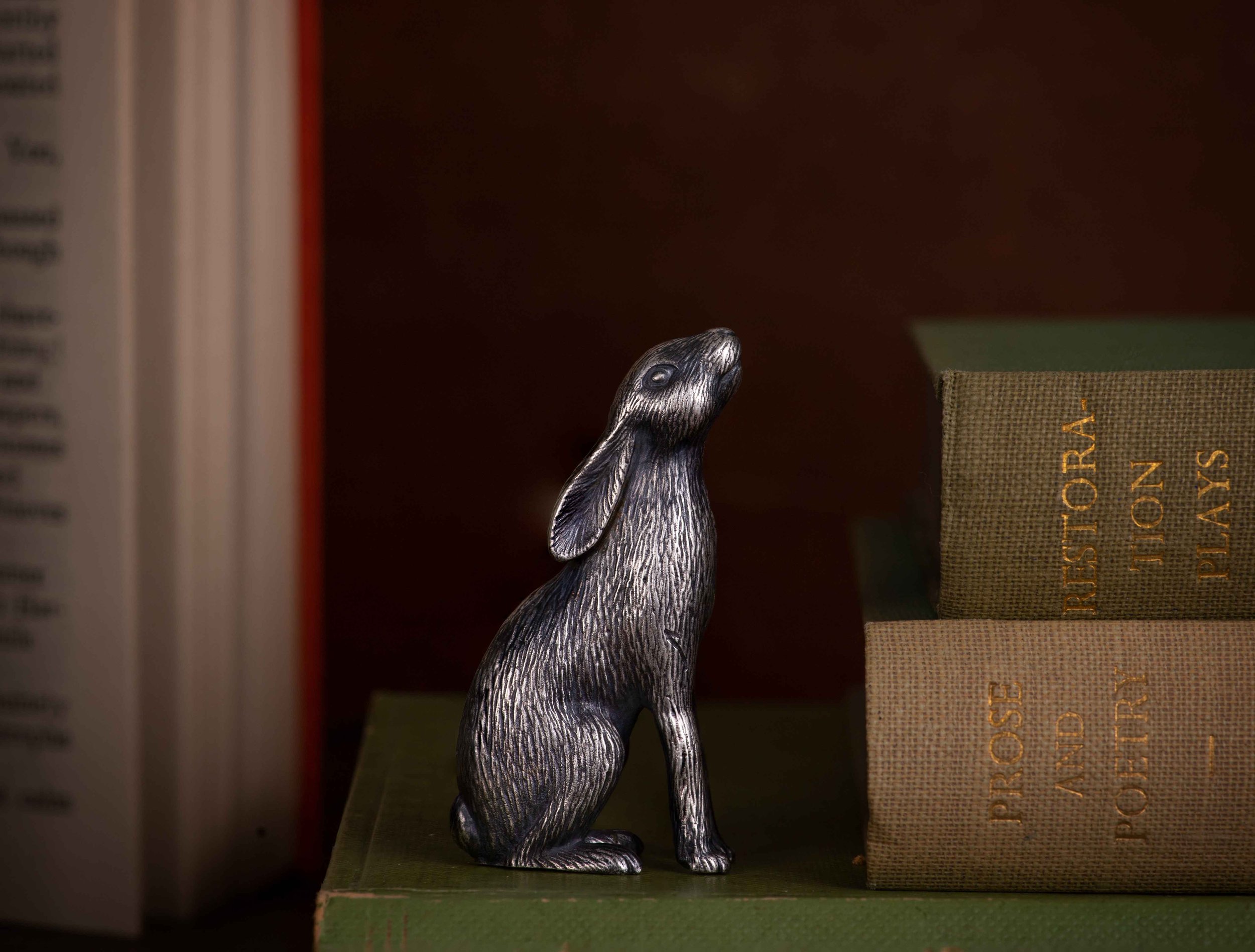 Silver rabbit figurine next to stacked books