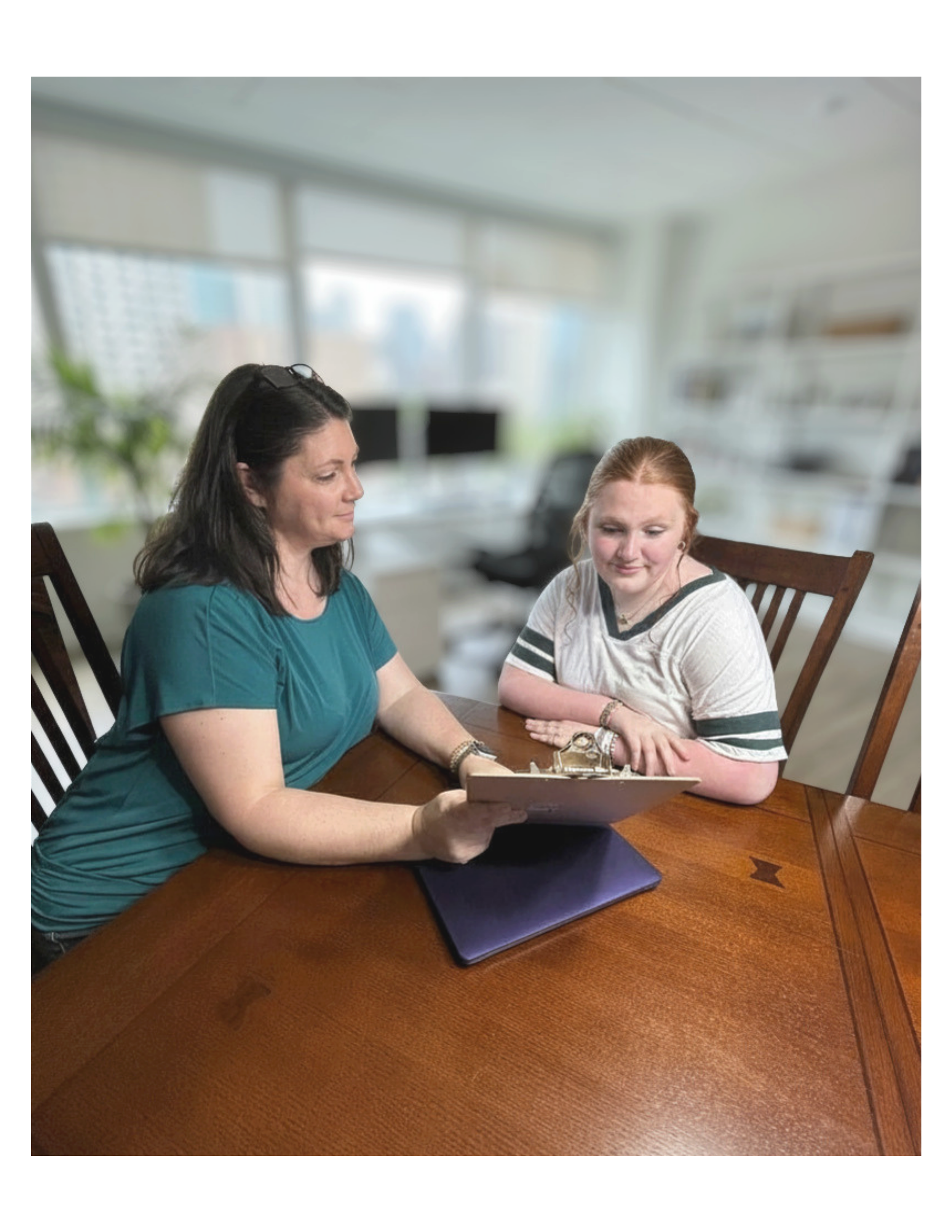 Therapeutic recreation specialist working one-on-one with a young client at Restoration and Recreation, reviewing personalized therapy goals in a warm office setting