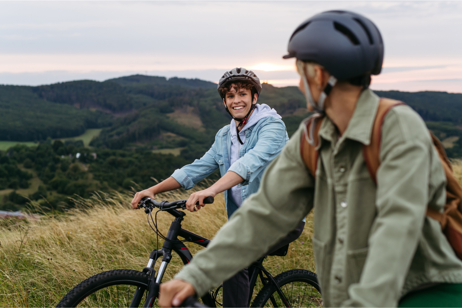 Two young people biking together outdoors in a scenic landscape, representing real-life recreational activities that support executive functioning skill development during summer.