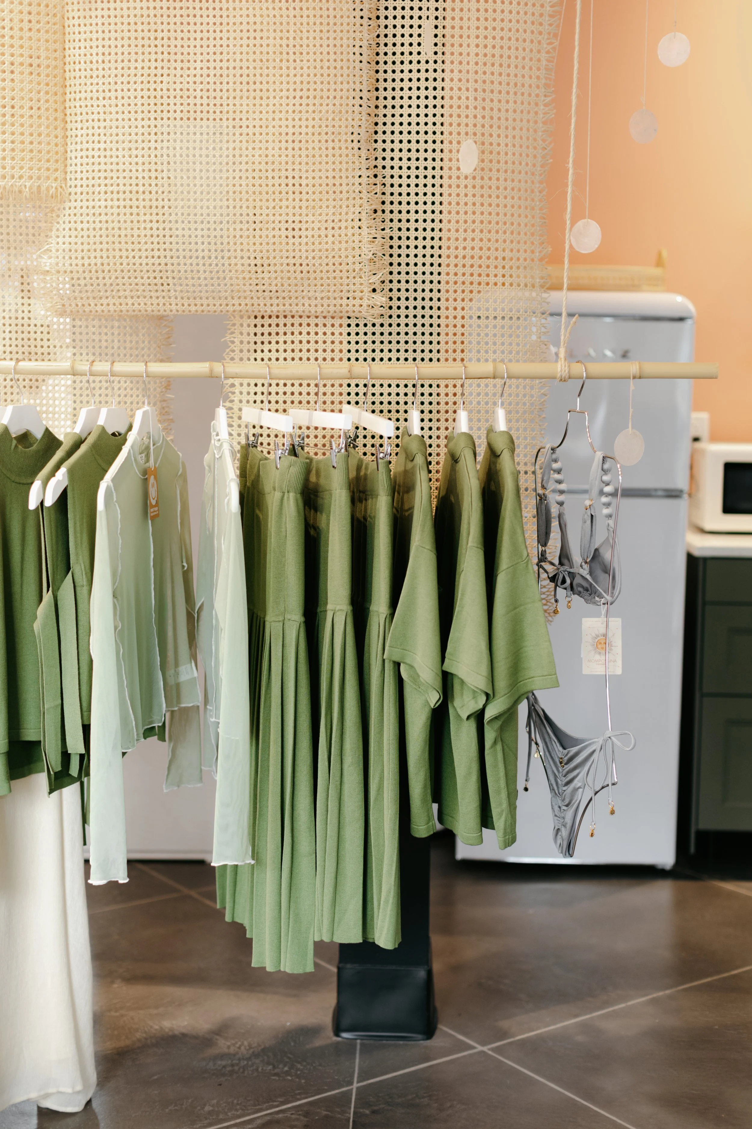 Clothing rack holding numerous green luxurious shirts, dresses, and pants. DistriktF Park City Brand Pop-Up Rental Space.