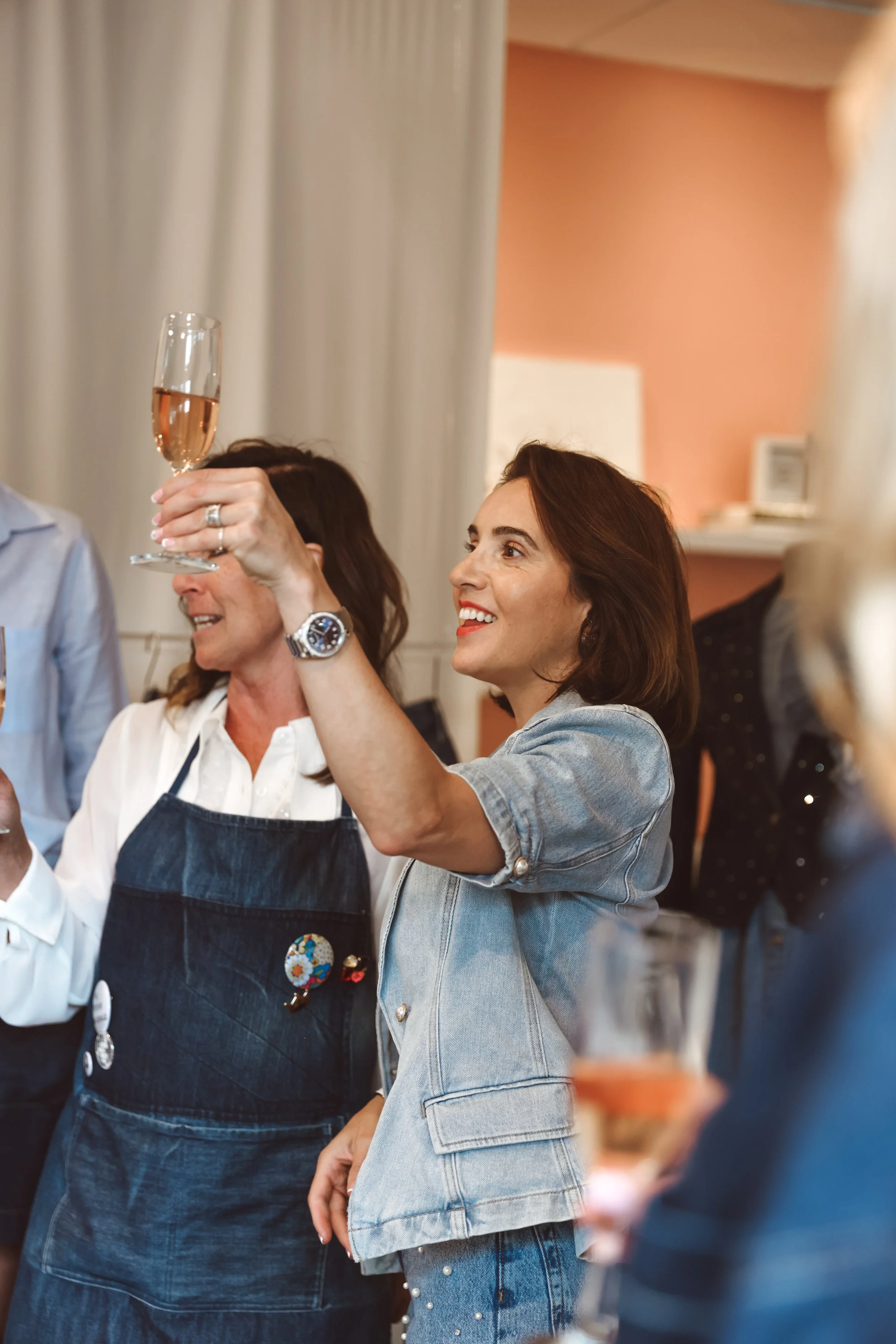 Woman holding a glass of champagne, toasting and smiling to a group of women. DistriktF Park City Utah Event Rental Space.