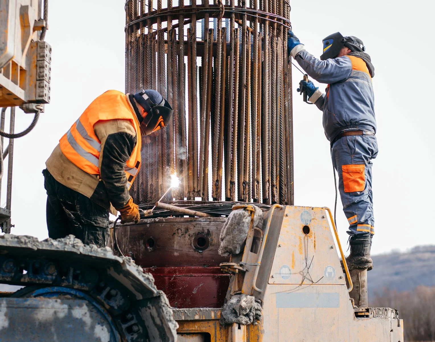 2 men on a bridge under construction welding steel