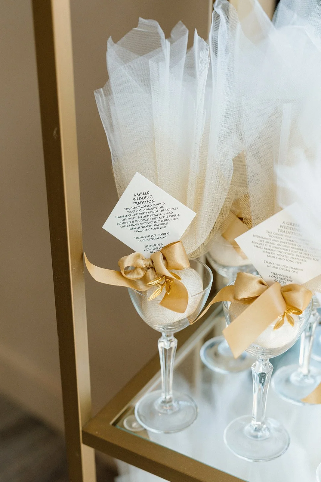 Wedding favors are on display in a coupe glass at a wedding reception.