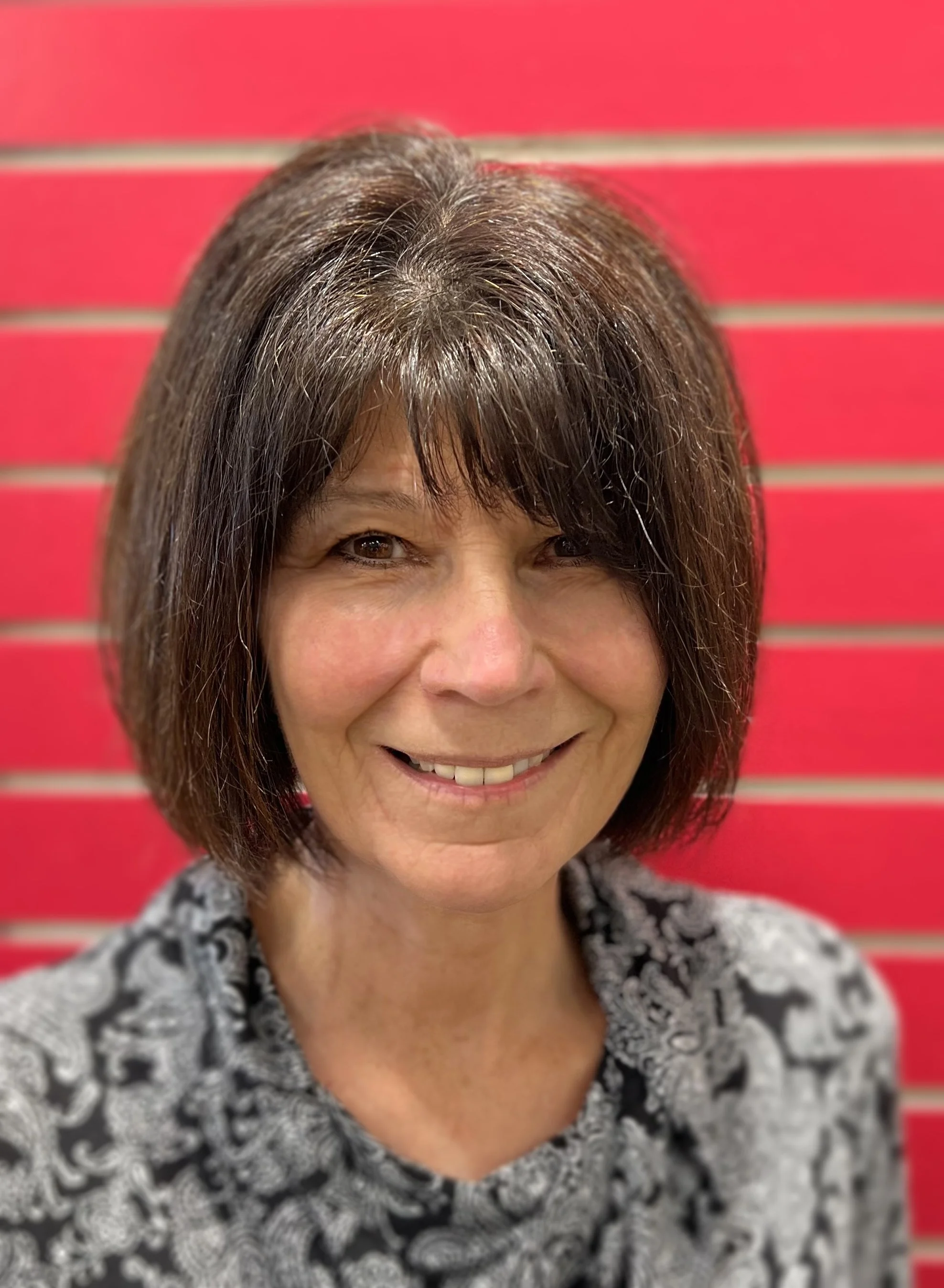 Judy standing in front of a red background and smiling