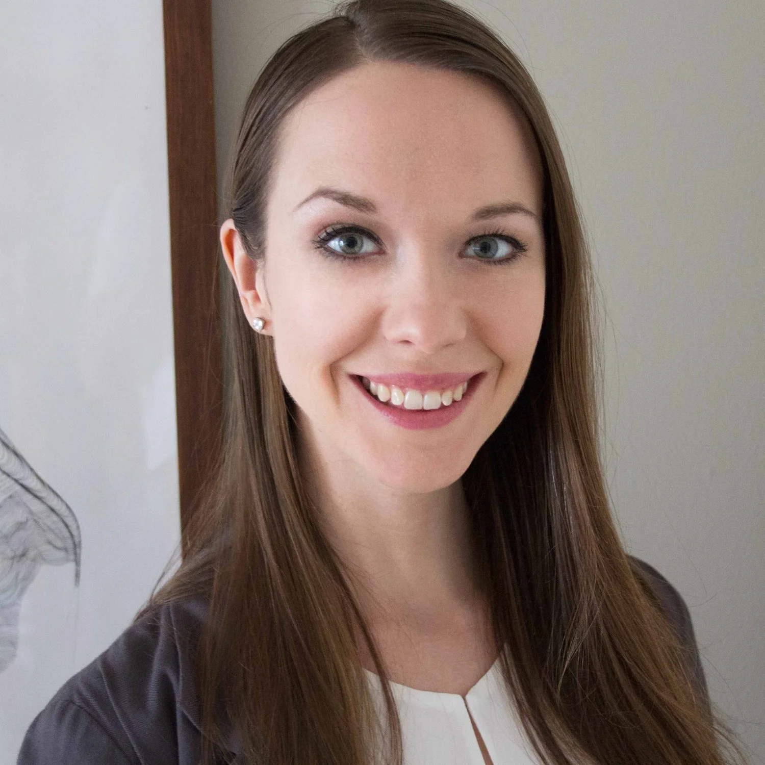 Professional portrait of Kirsten Langereis in a circular frame. She is smiling with a wood-framed, black and white art piece hanging on the wall in the background.
