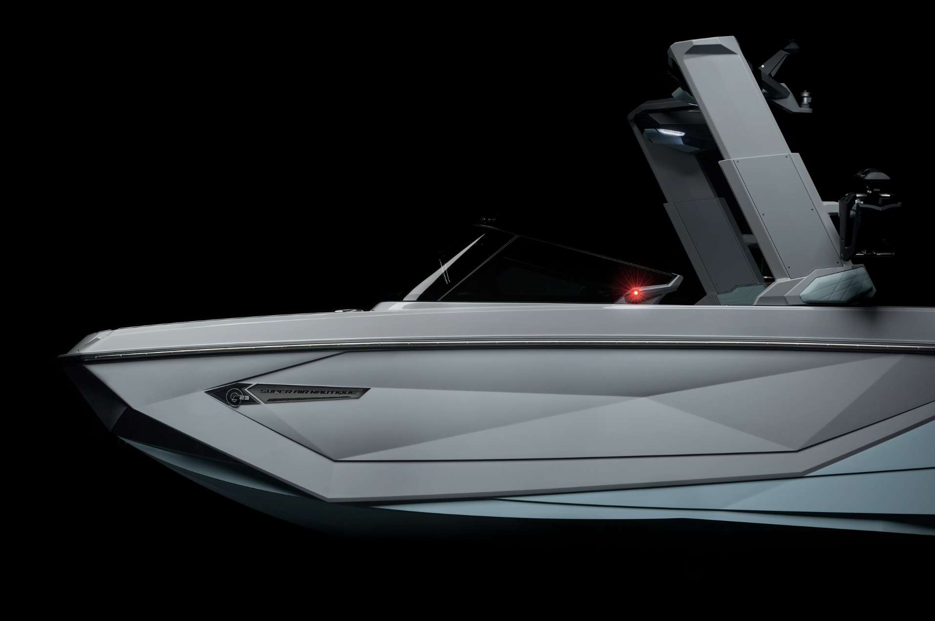 A sleek, modern wakeboard boat with a gray hull and advanced design features against a black background.