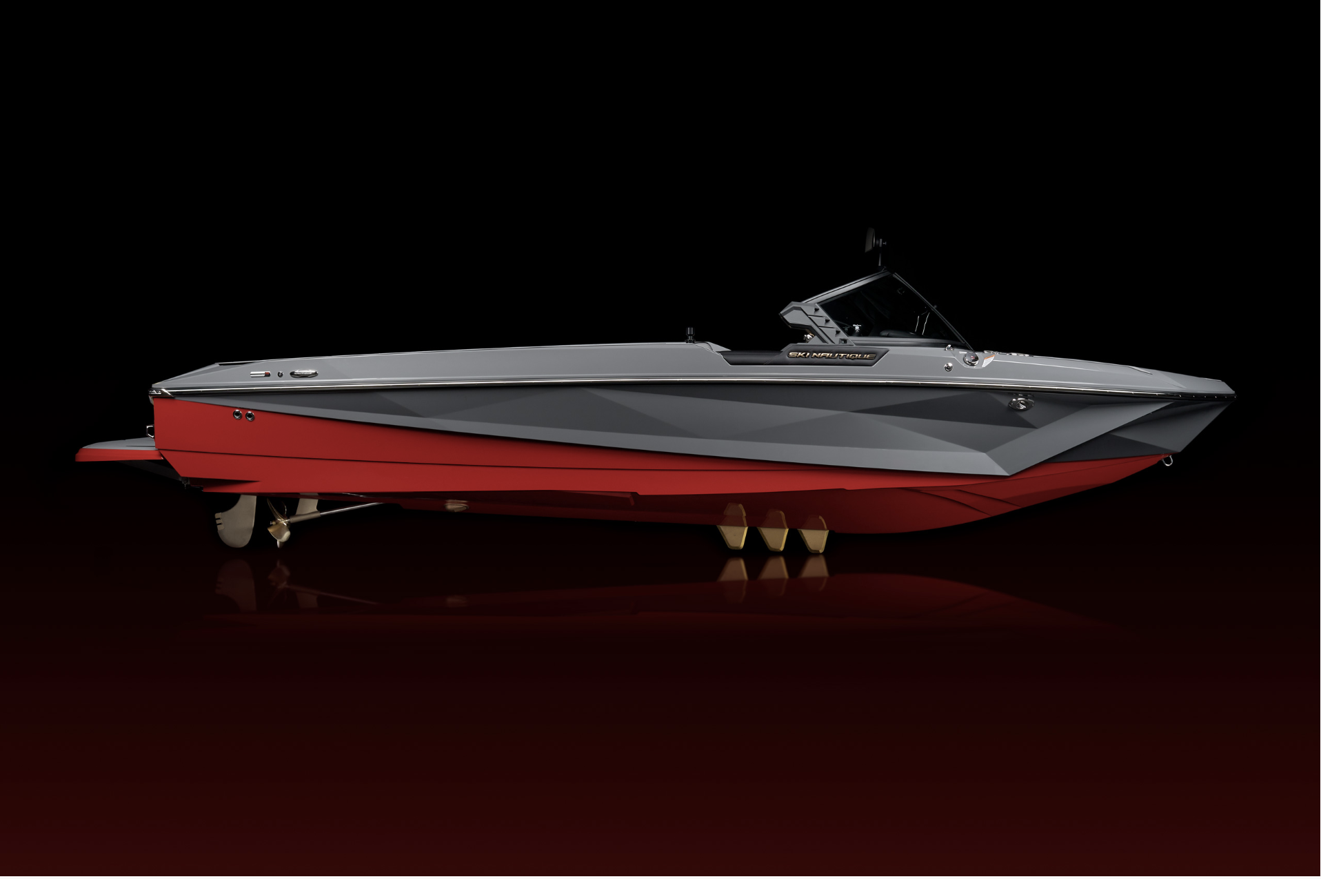 A sleek, modern ski boat with a gray and red hull, displayed against a black background.