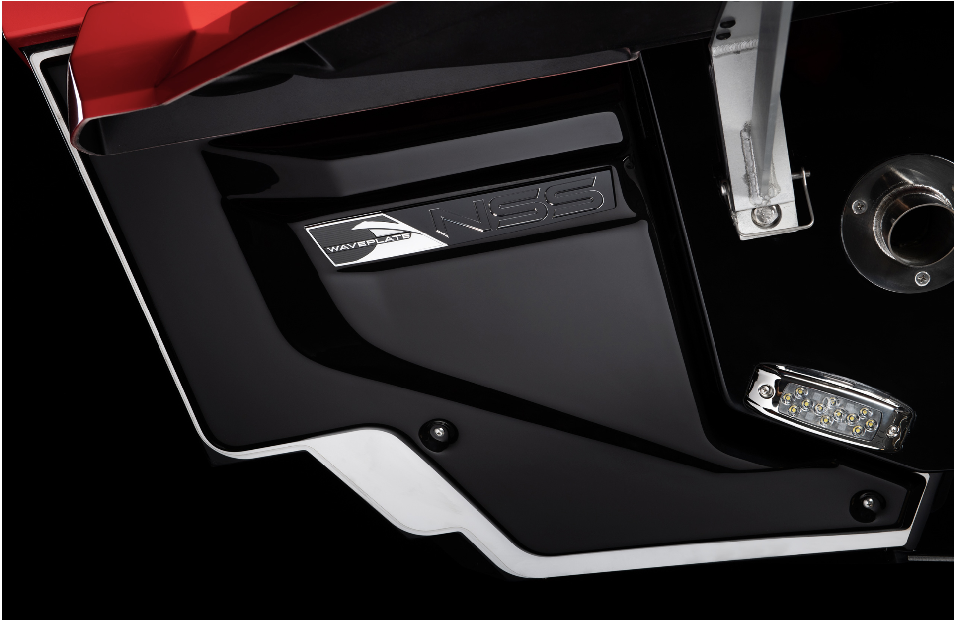 Close-up of a boat with a focus on the exhaust pipe, LED lights, and a label that reads 'Waveplate NISS' on a black and red body.