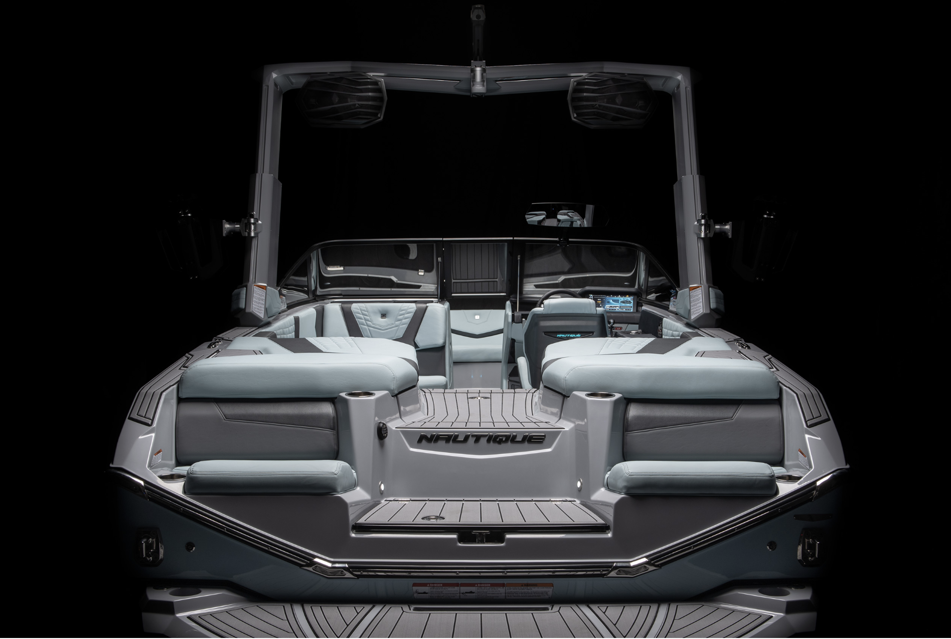 A modern Nautique wakeboarding boat with seating and a control panel, set against a black background.