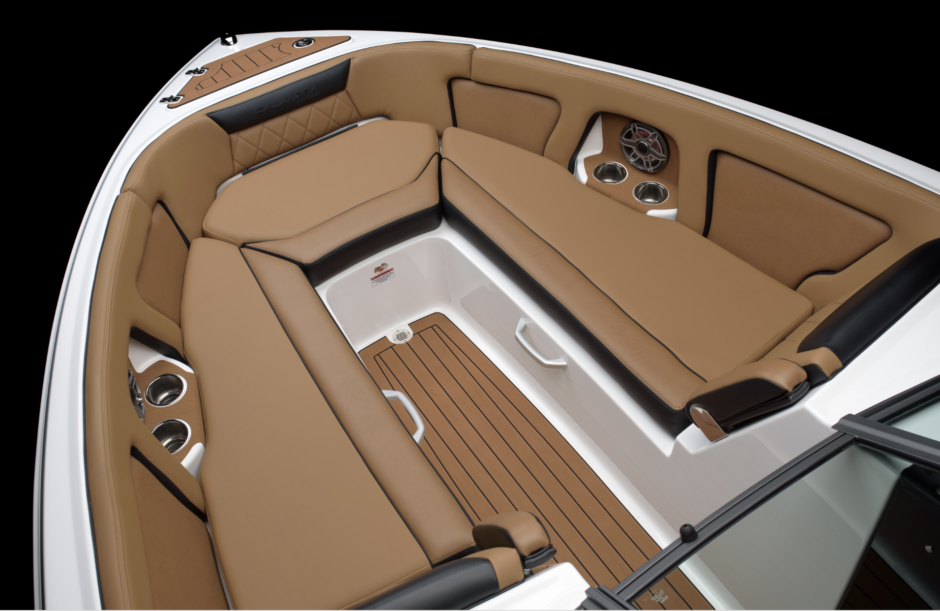 The interior of a boat with brown cushioned seats arranged in a U-shape, cup holders, a speaker, and a wooden floor.