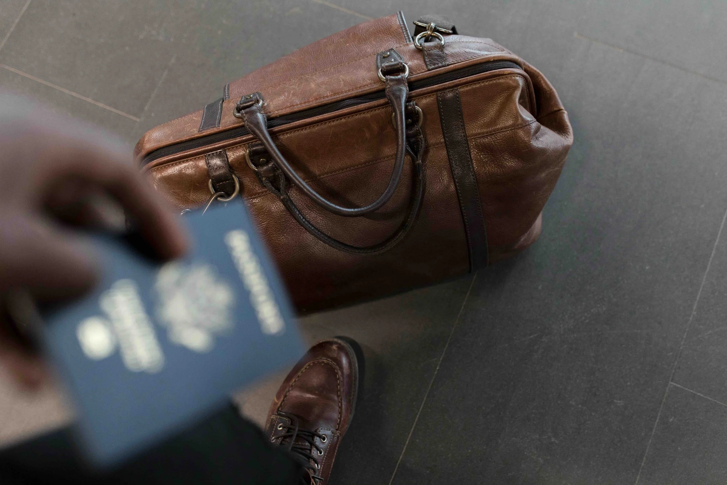 man's leg with a passport and brown bag