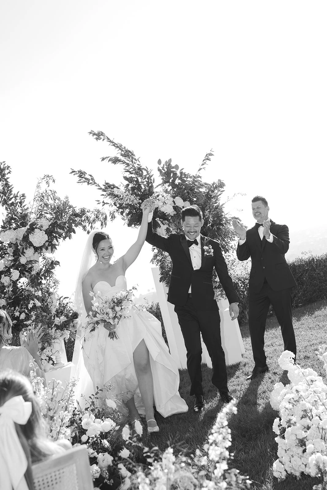 Bride and groom hand-in-hand with loved ones cheering