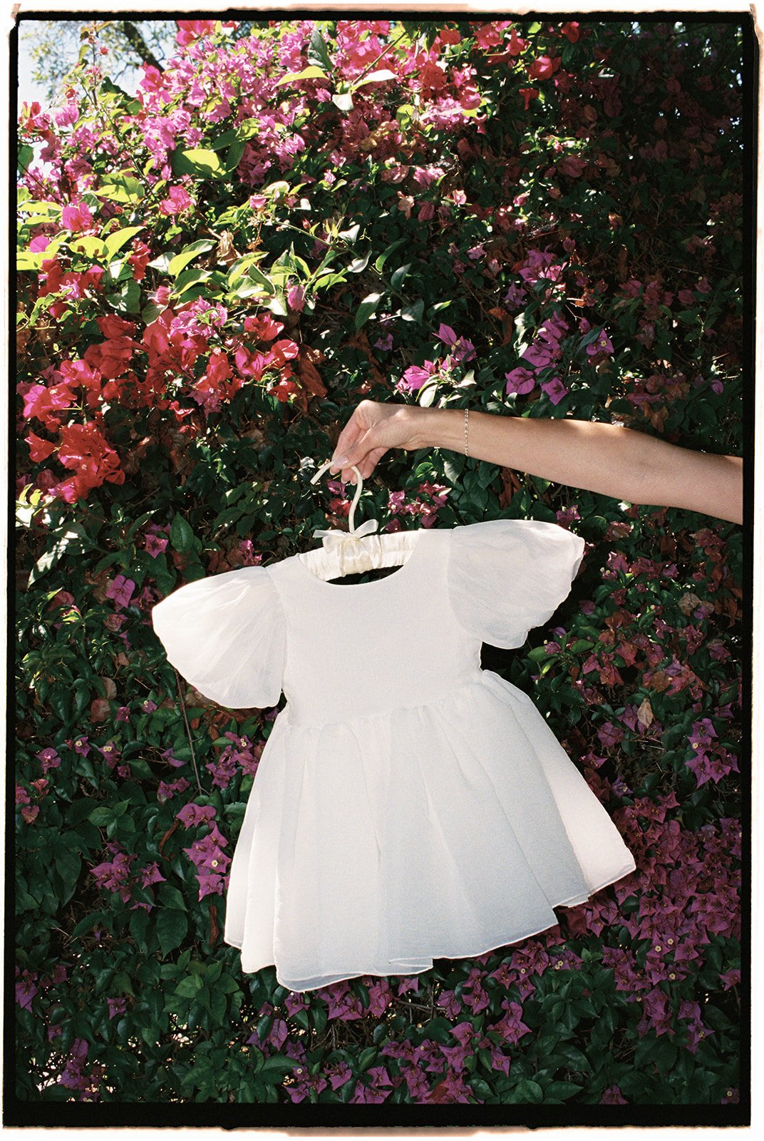 The pink flowers contrast with the dainty flower girl dress. 35 mm film. 
