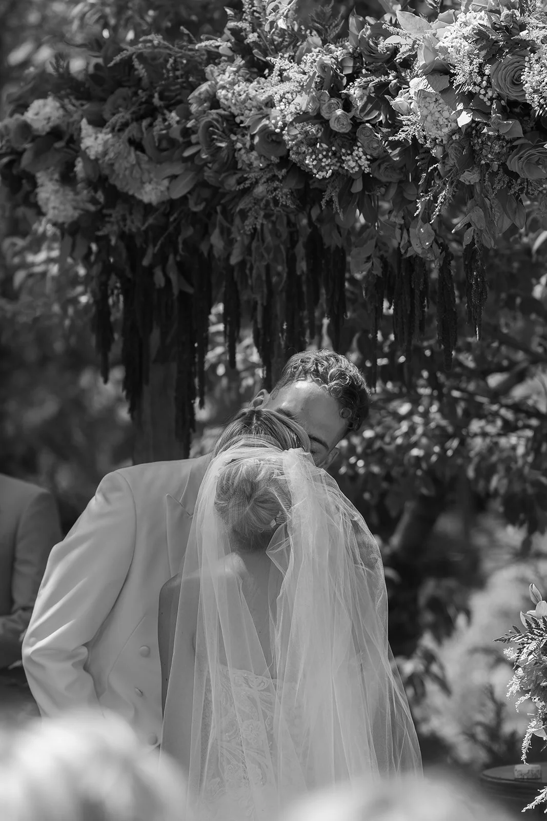 The bride and groom share their first kiss as a married couple under a draping floral arch in Big Bear California