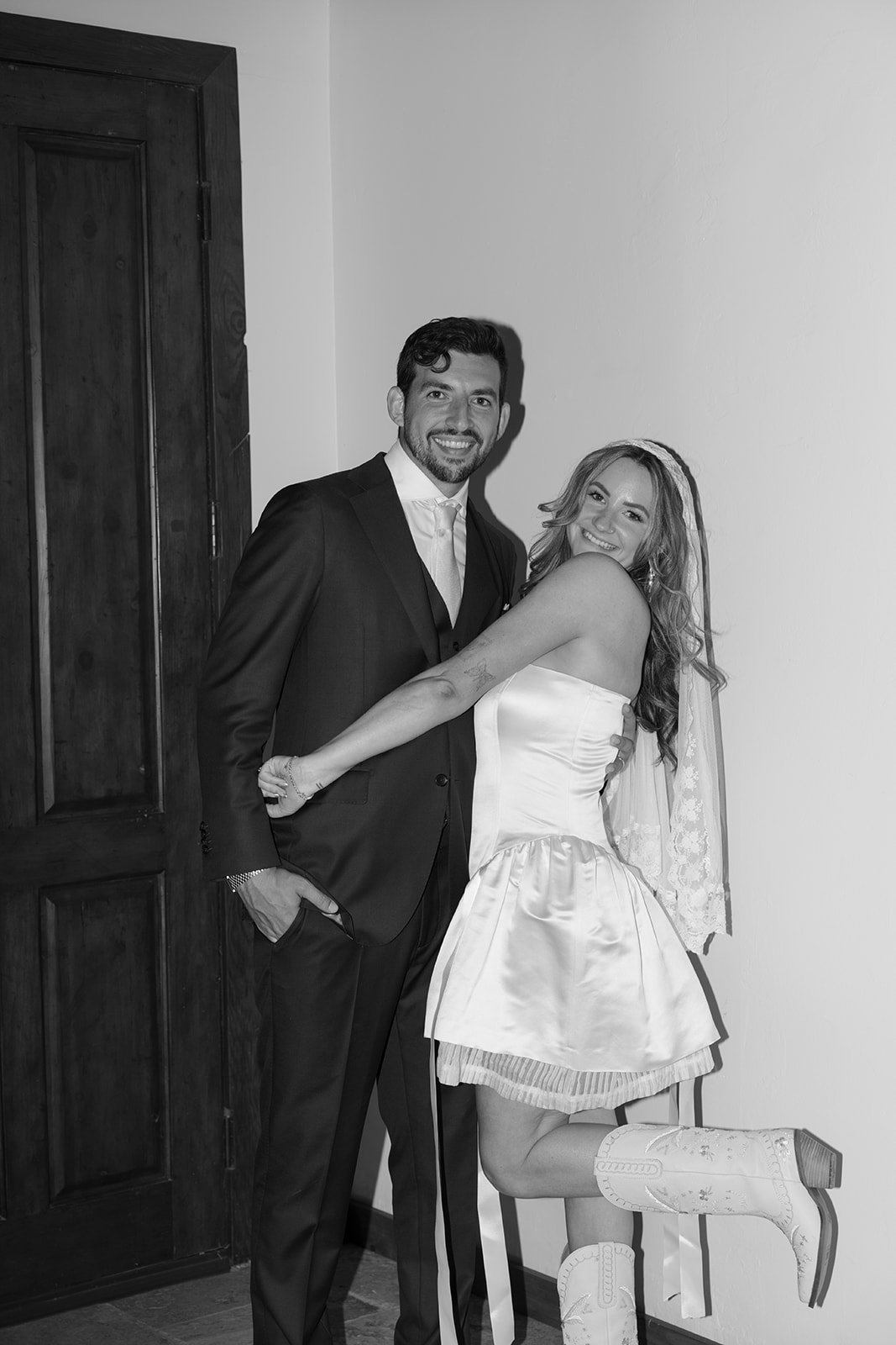 Reception look: custom mini bridal dress, cowgirl boots, and a mantilla veil.