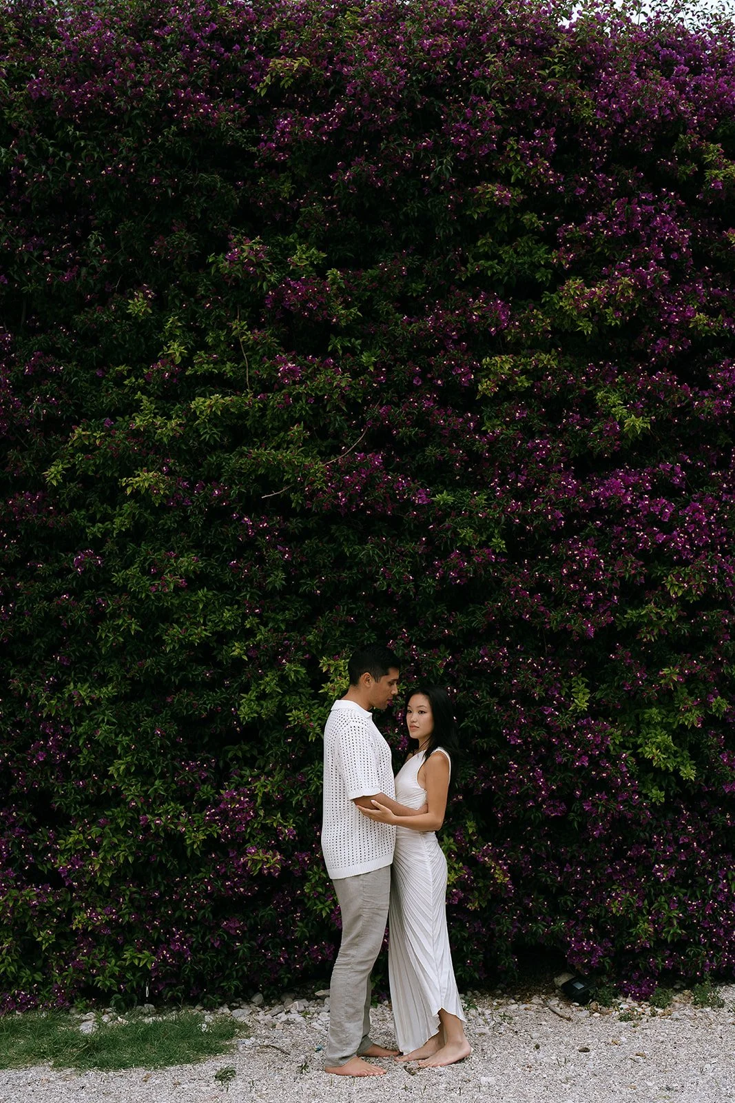 Couple in front of lush greenery bush on the Mediterranean Coast on the South of France during their destination engagement photoshoot