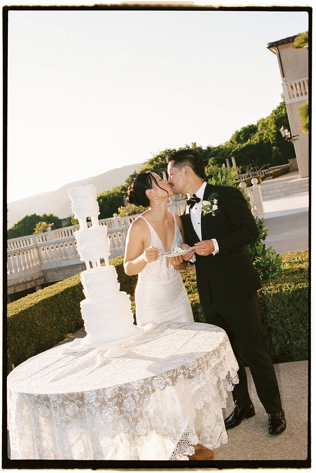 The bride and groom kissing by the cake.