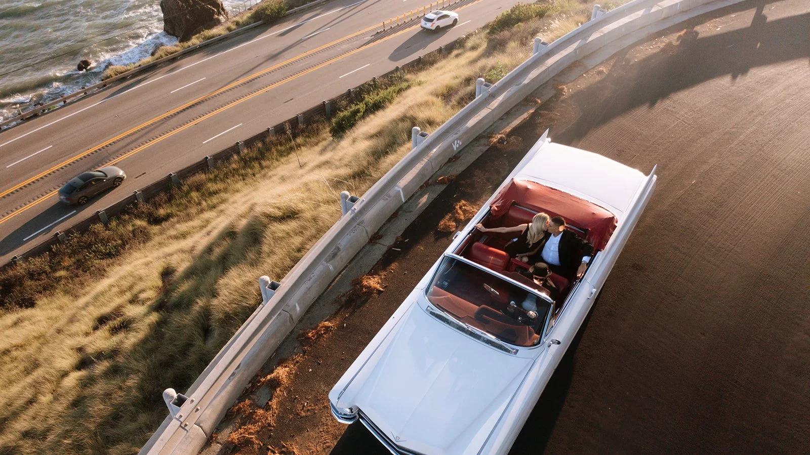 A couple kissing in the car driving on the coastline.