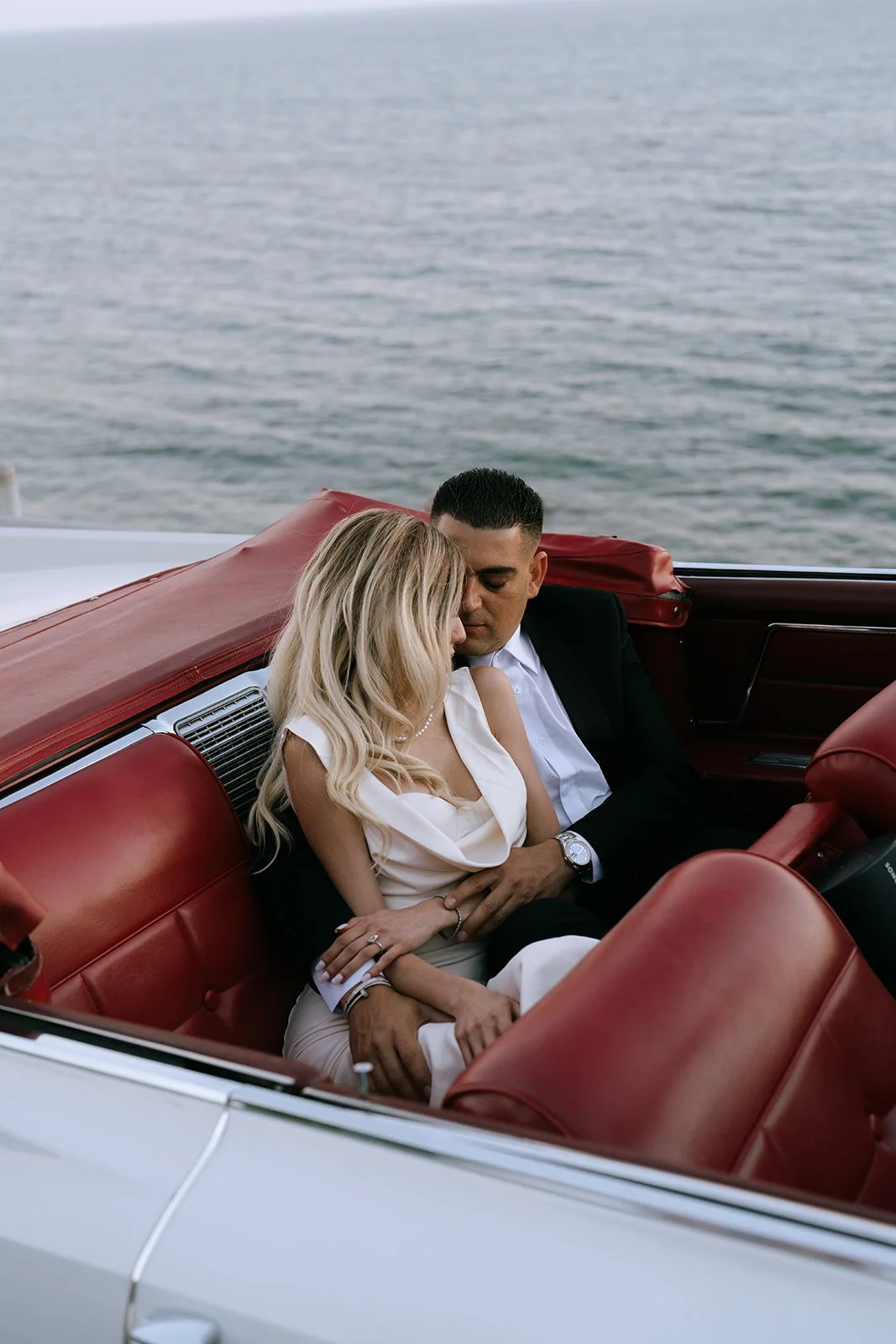 The bride and groom in an embrace in the back seat