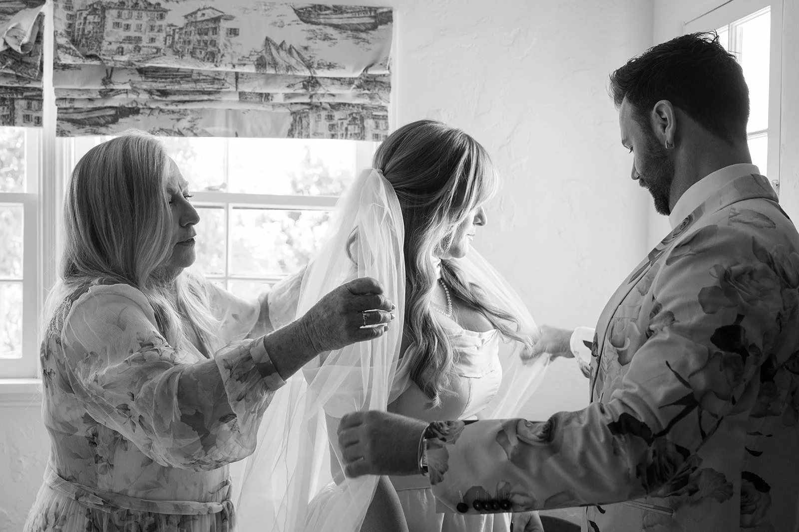 Mom and man of honor place the veil on bride.