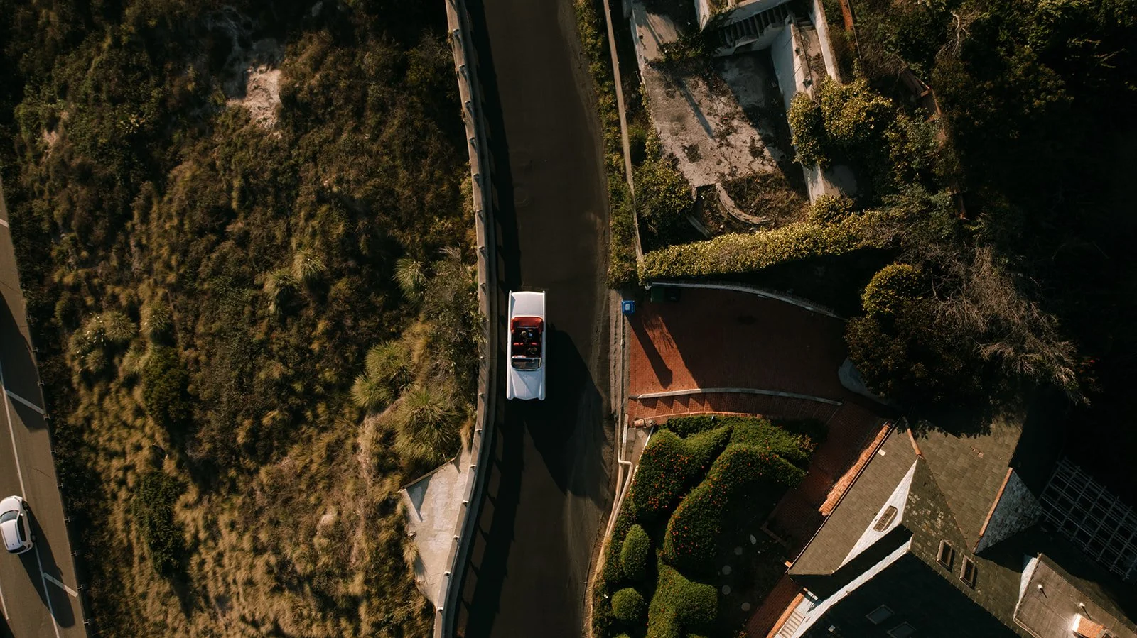 A drone shot showing a car driving down the coastline.