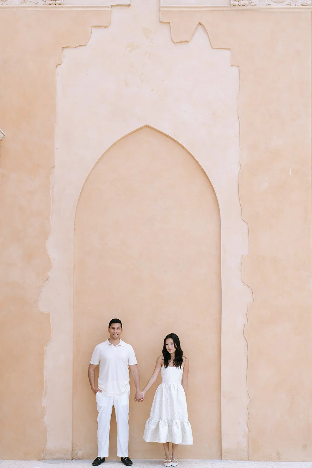 destination engagement session, couple is holding hands in front of the pink walls of the Villa Ephrussi on the Mediterranean Coast of France