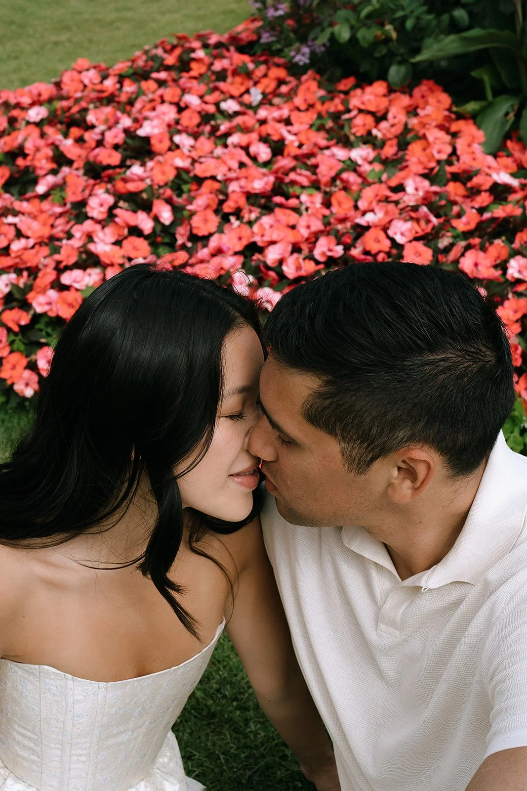 Couple kisses surrounded by pink impatien flower beds in the French garden of the Villa Ephrussi