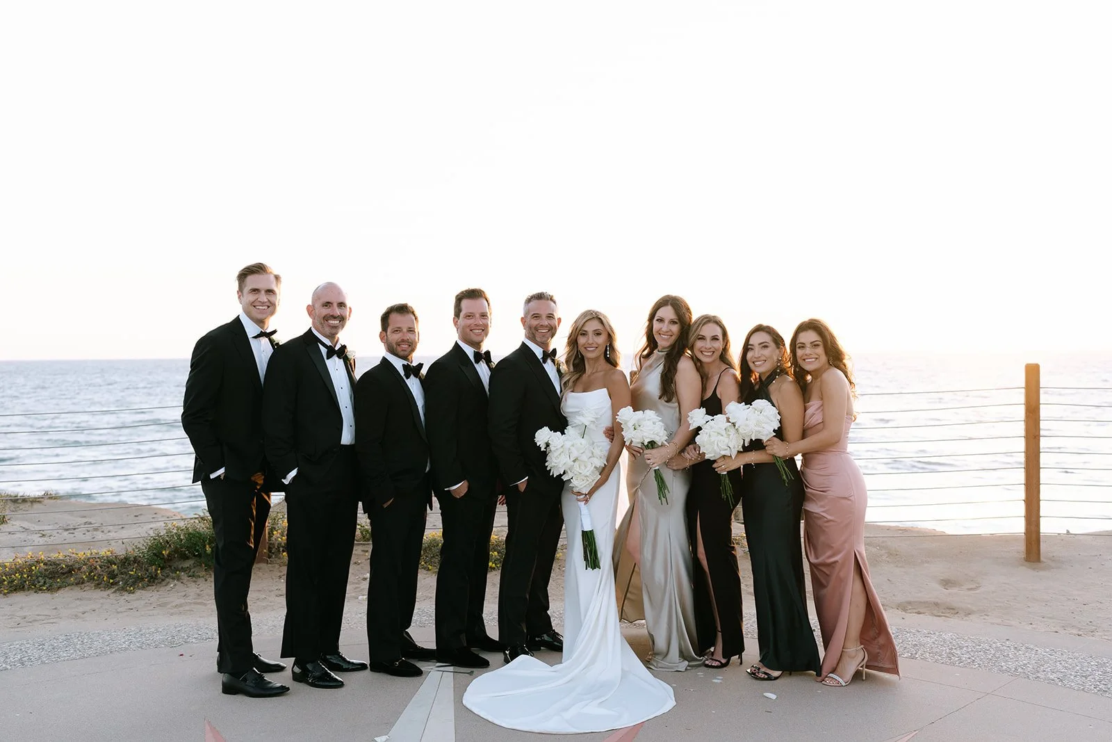 modern luxury wedding party smiles together at sunset