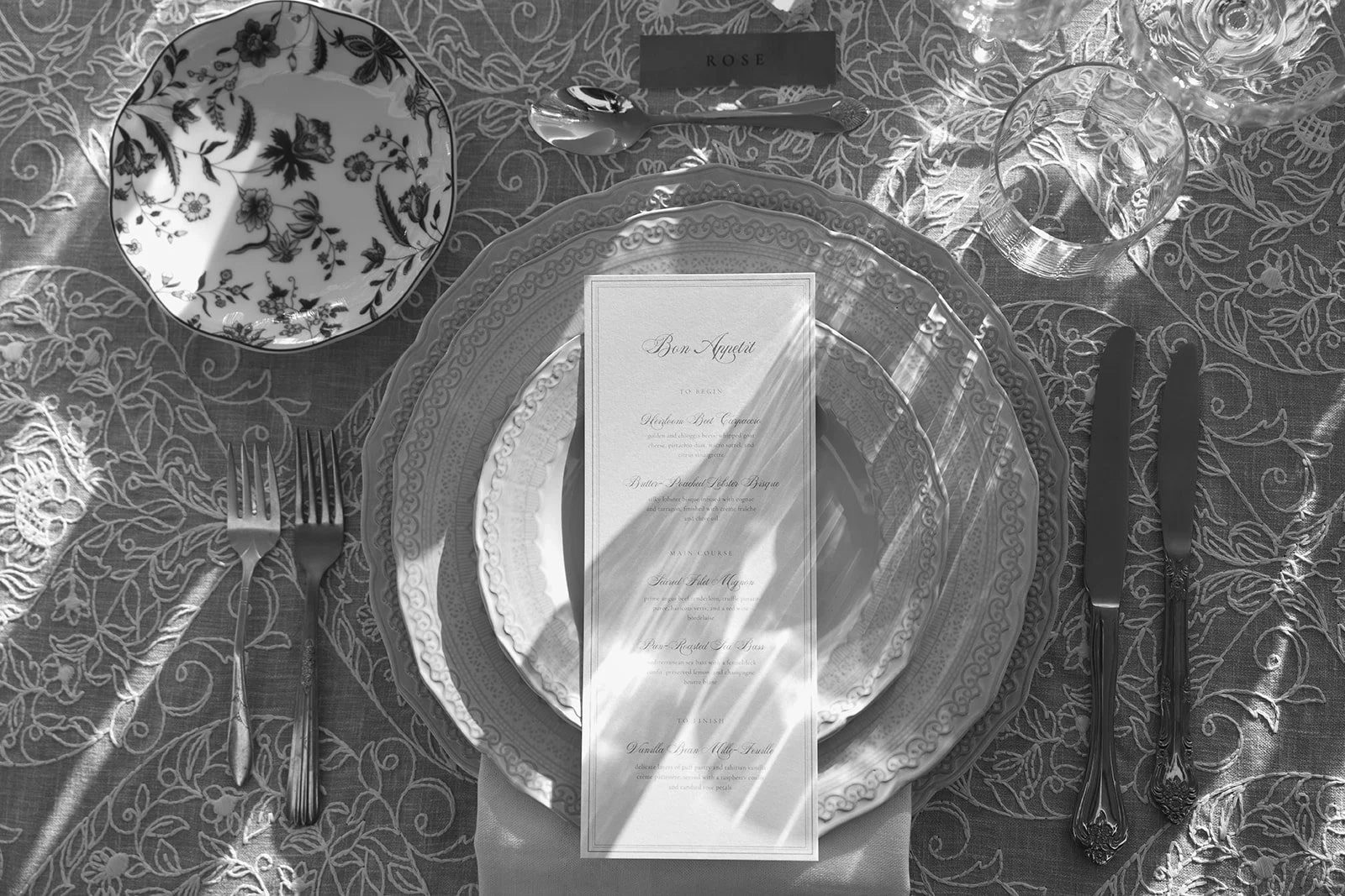 Place setting details: custom menu, china, silverware, and lace linens.