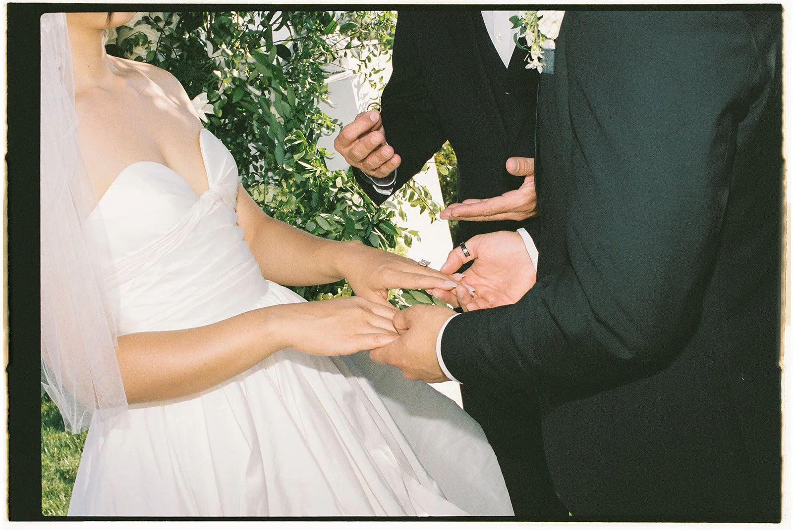The bride and groom holding hands and exchanging rings