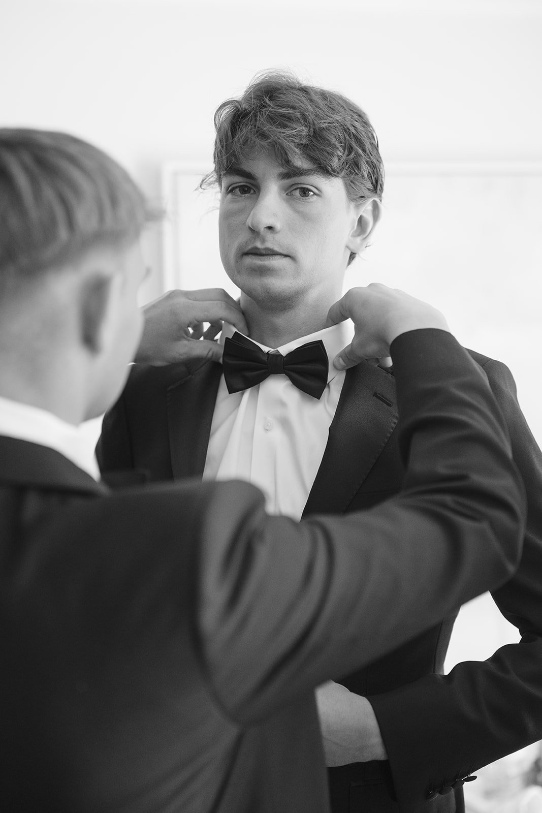 The groom getting his bow tie fixed