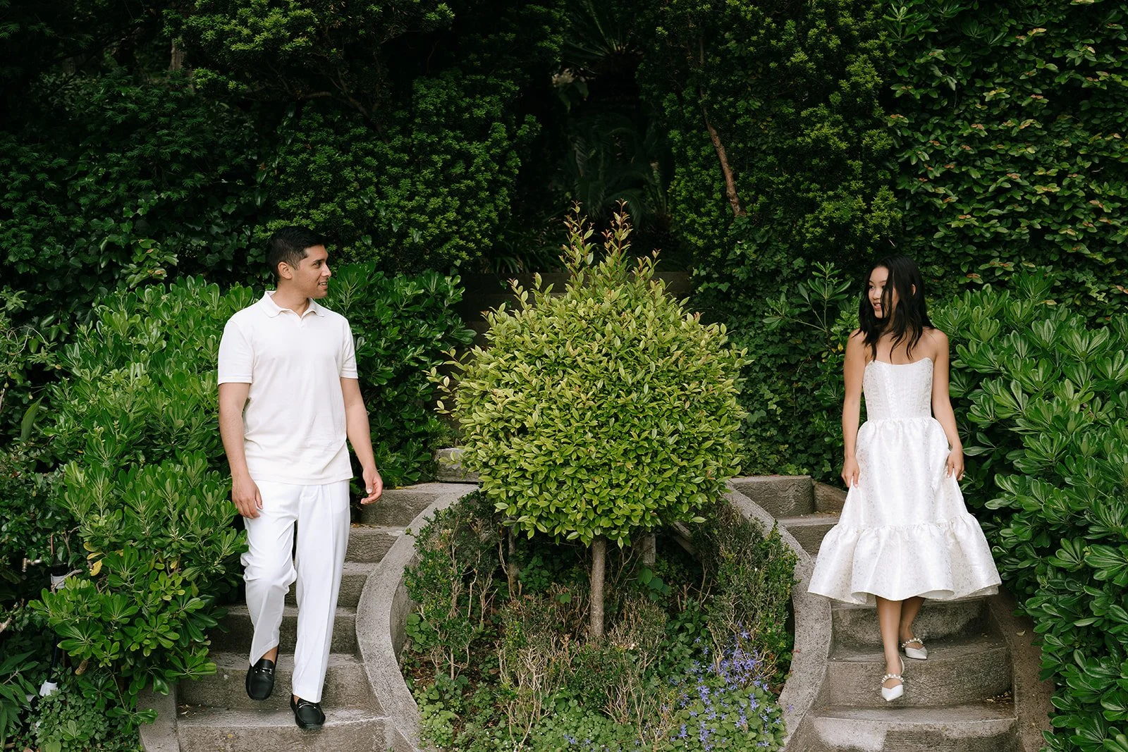 Photo of soon to be bride and groom descending a stone staircase split two ways between a tree in one of the gardens of the Villa Ephrussi
