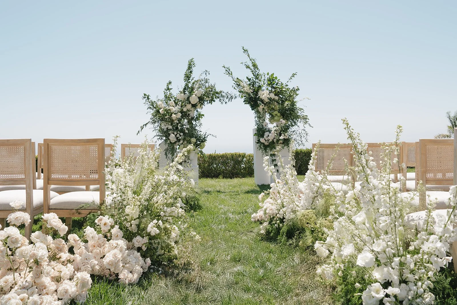 White flowers lining the aisle and a floral arch
