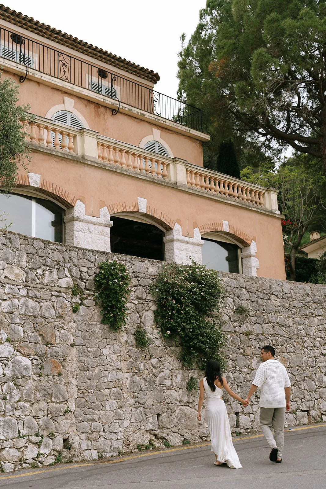 Couple walking hand in hand along Provencal-style villas of the French Riviera near the Plage de Passable or Passable Beach in St-Jean-Cap-Ferrat in France