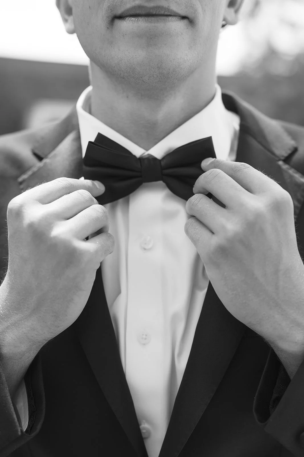 A close-up of the groom fixing his tie