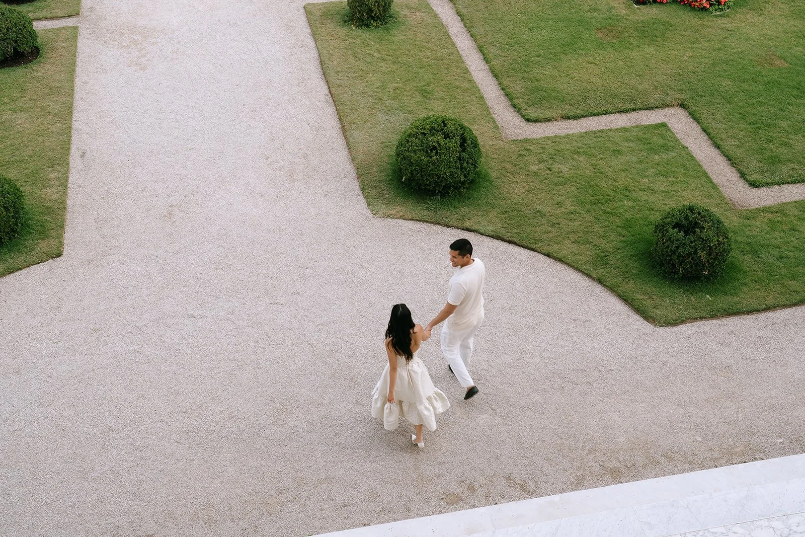 Birds eye view of a couple walking hand in hand through the gradens of the Villa Ephrussi on the South of France